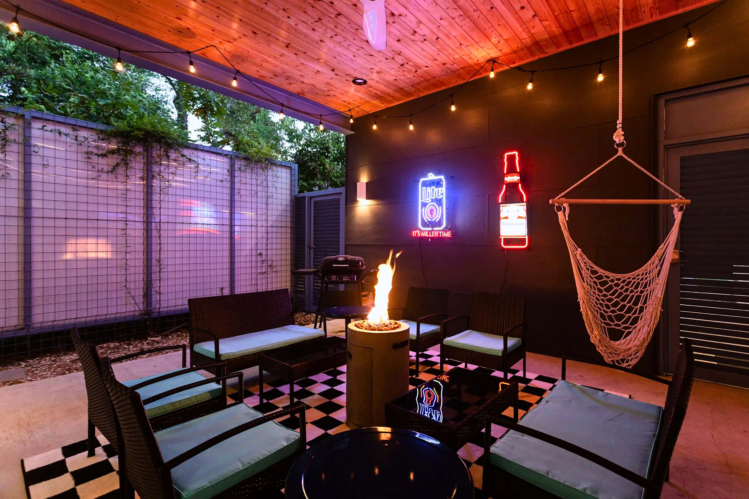 Covered lounge with firepit centerpiece, BBQ grill, and mesh hammock, built for relaxed hangouts rain or shine