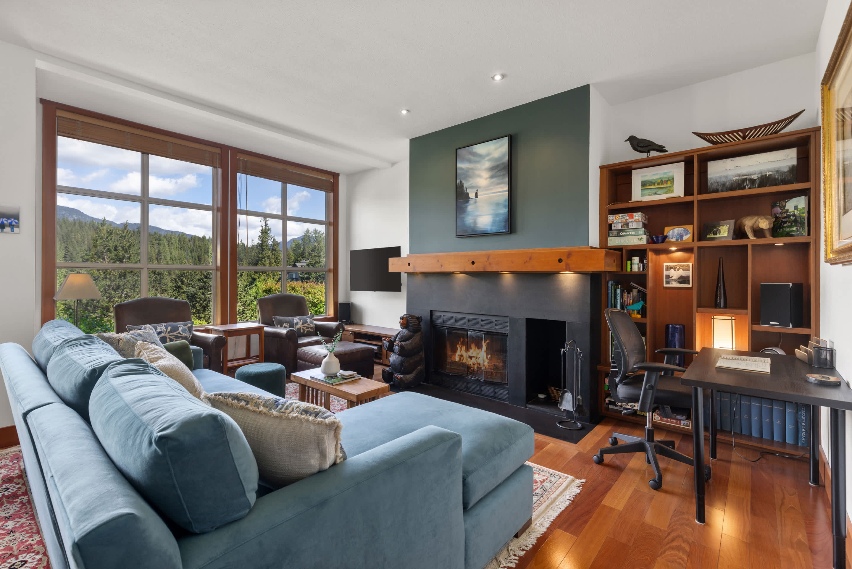 - Bright open-concept living room with scenic forest views 
- Plush seating, large windows, and warm natural light throughout 
- Relax by the fire after a day of skiing or hiking nearby 