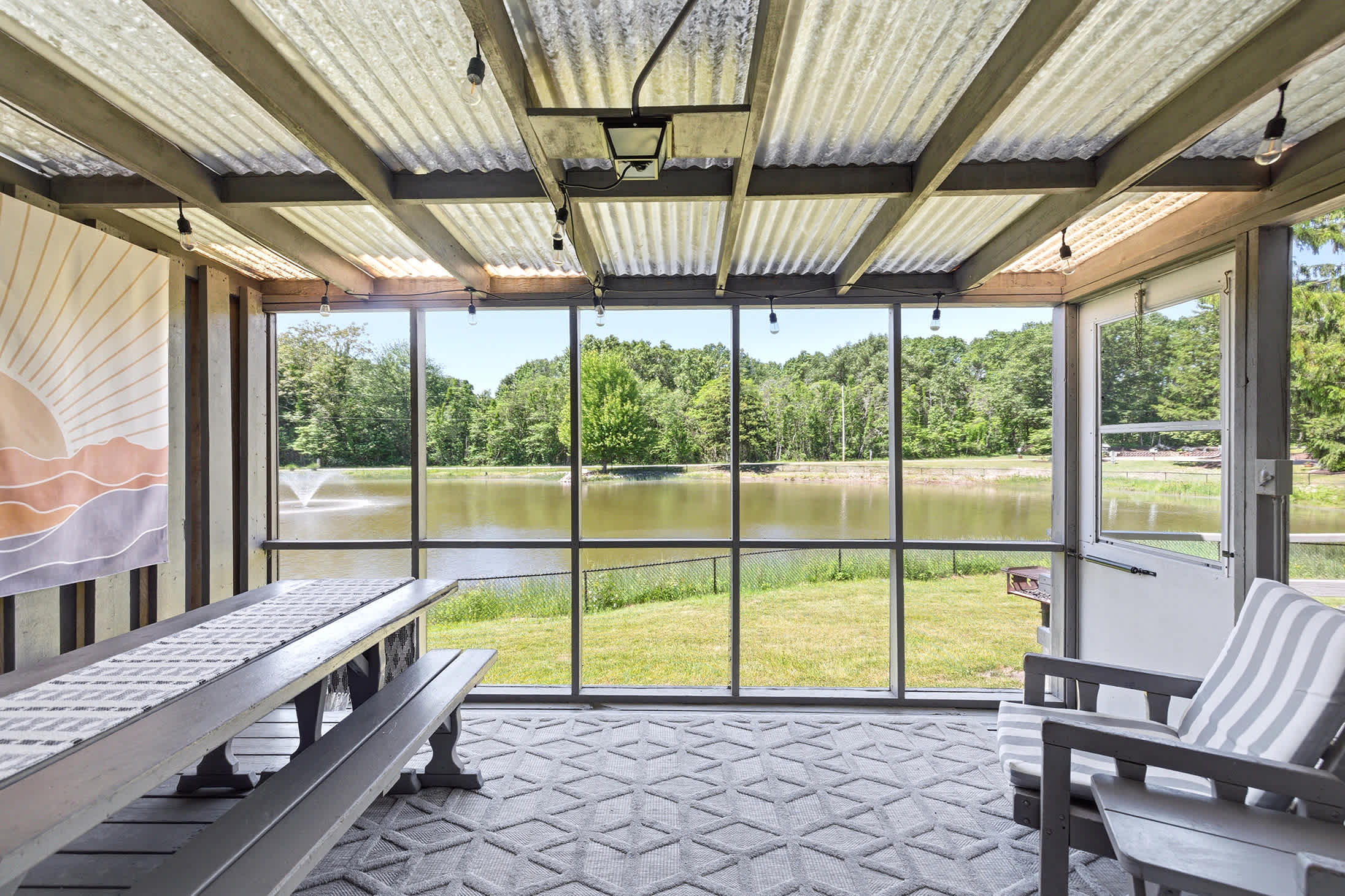 Screened porch with pond views for comfortable outdoor dining.