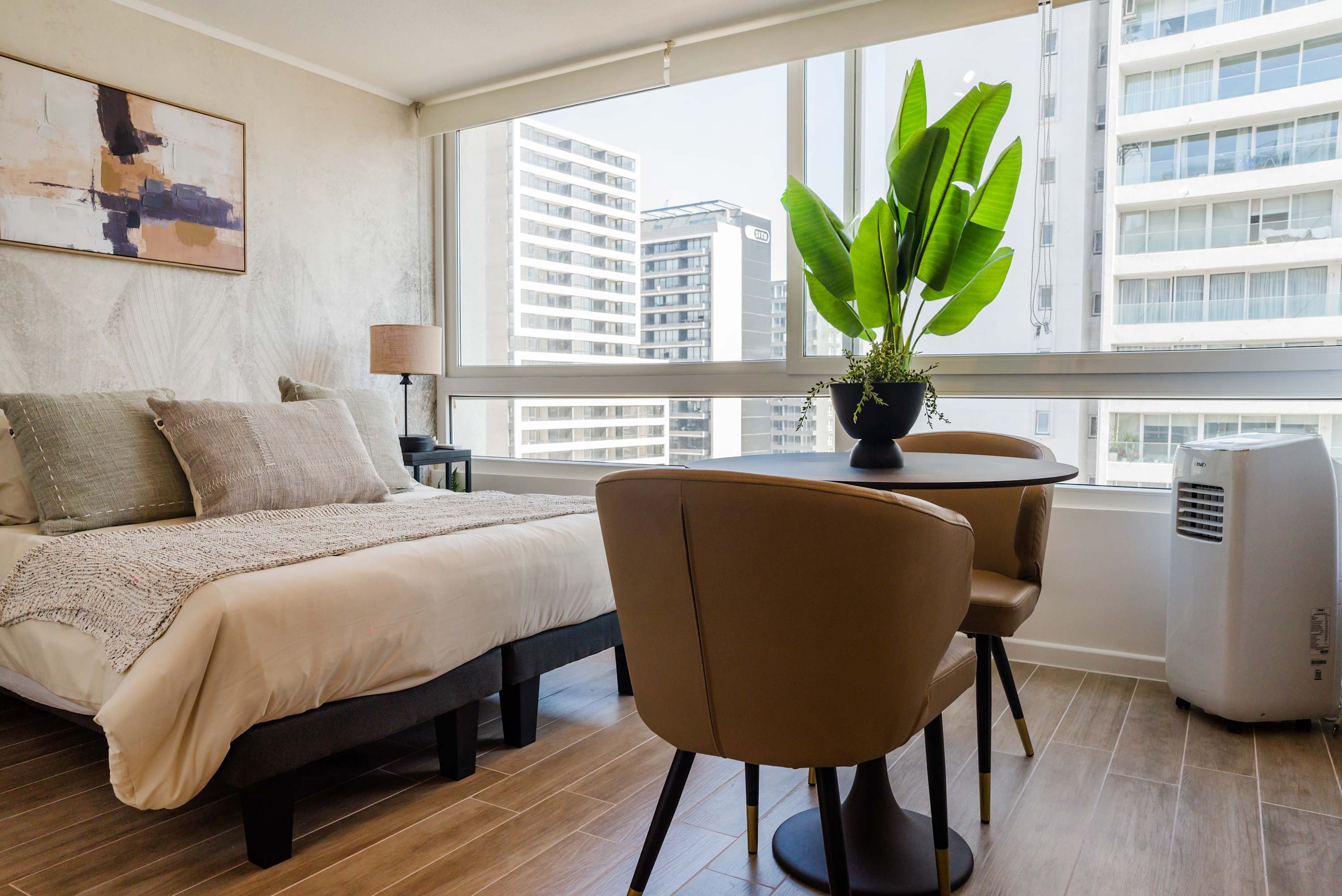 Relax in this cozy studio with stunning city views, featuring a comfortable bed and stylish seating area.