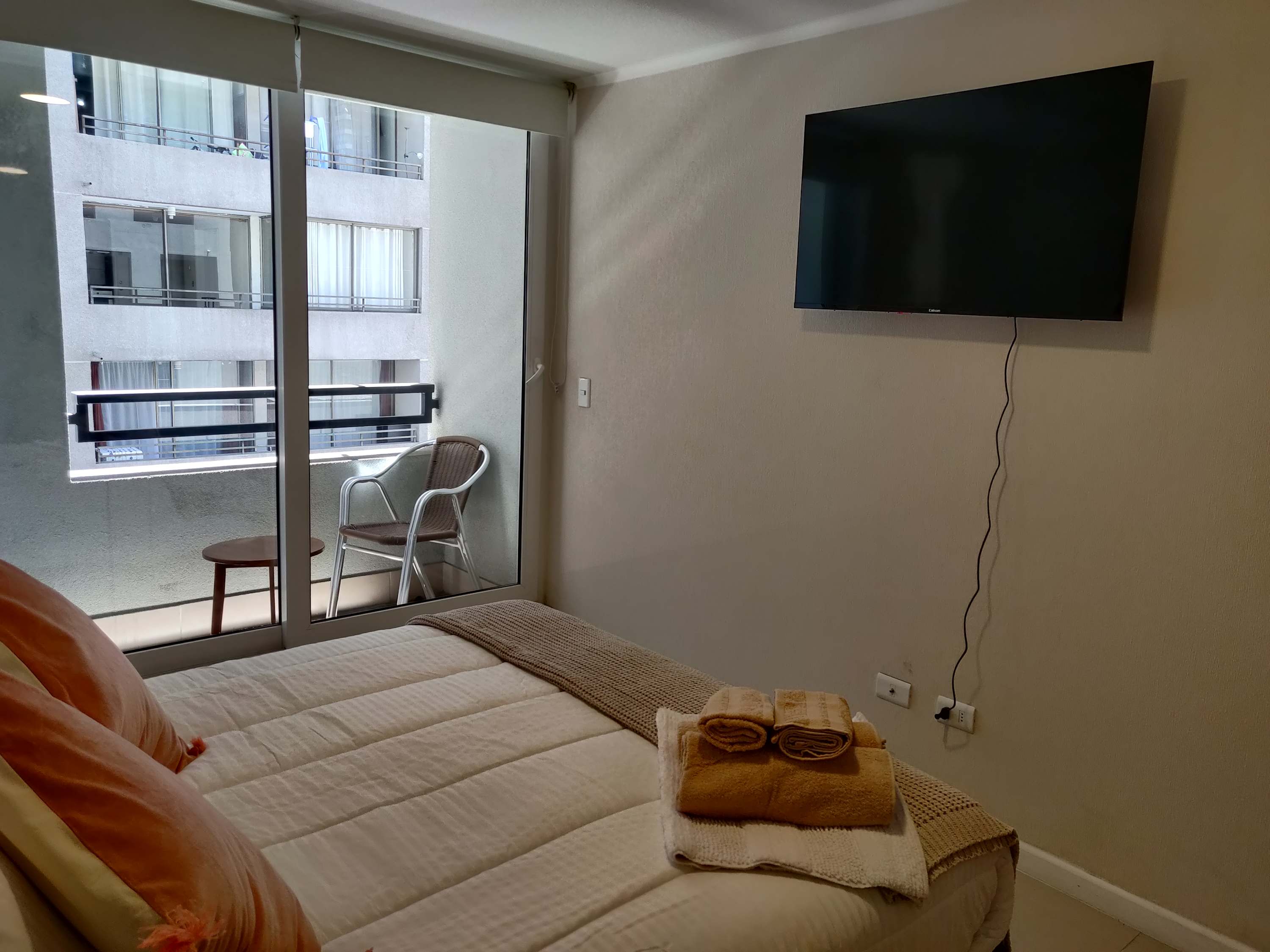Cozy bedroom with balcony access and a wall-mounted TV, perfect for relaxation.