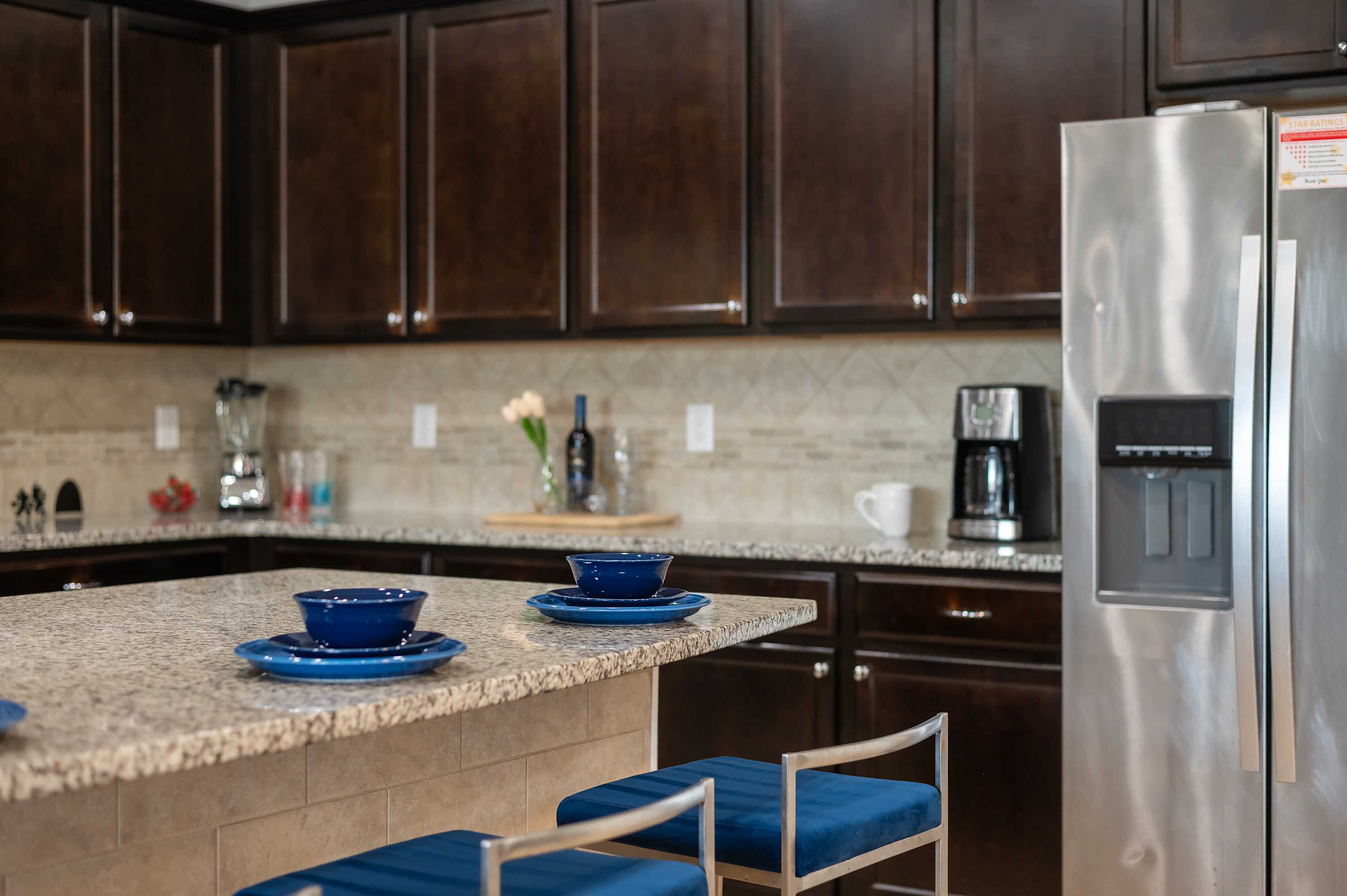 Kitchen counter detail w/ dark cabinetry & stainless steel fridge for easy entertaining.