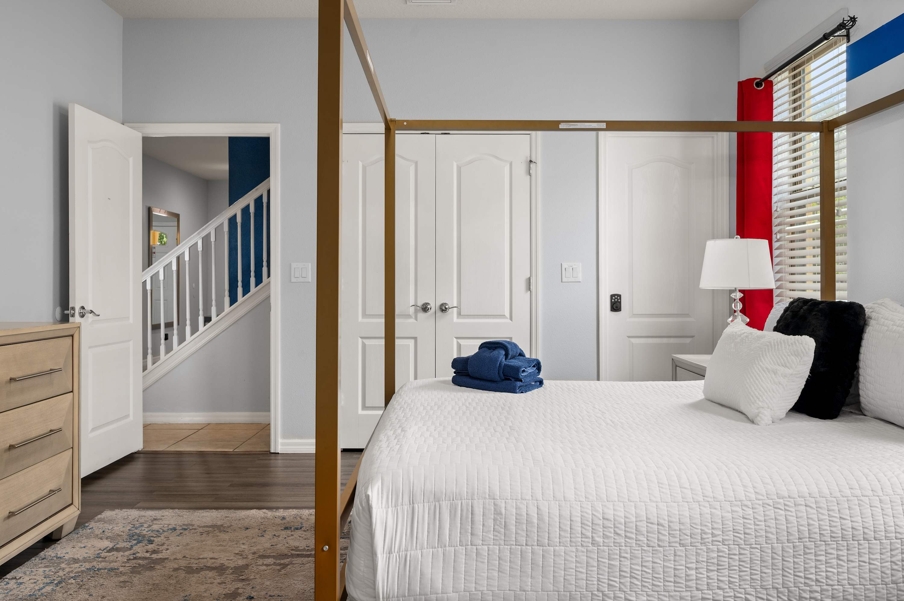 Elegant bedroom w/ gold four-poster bed & bold red curtains for a touch of drama.