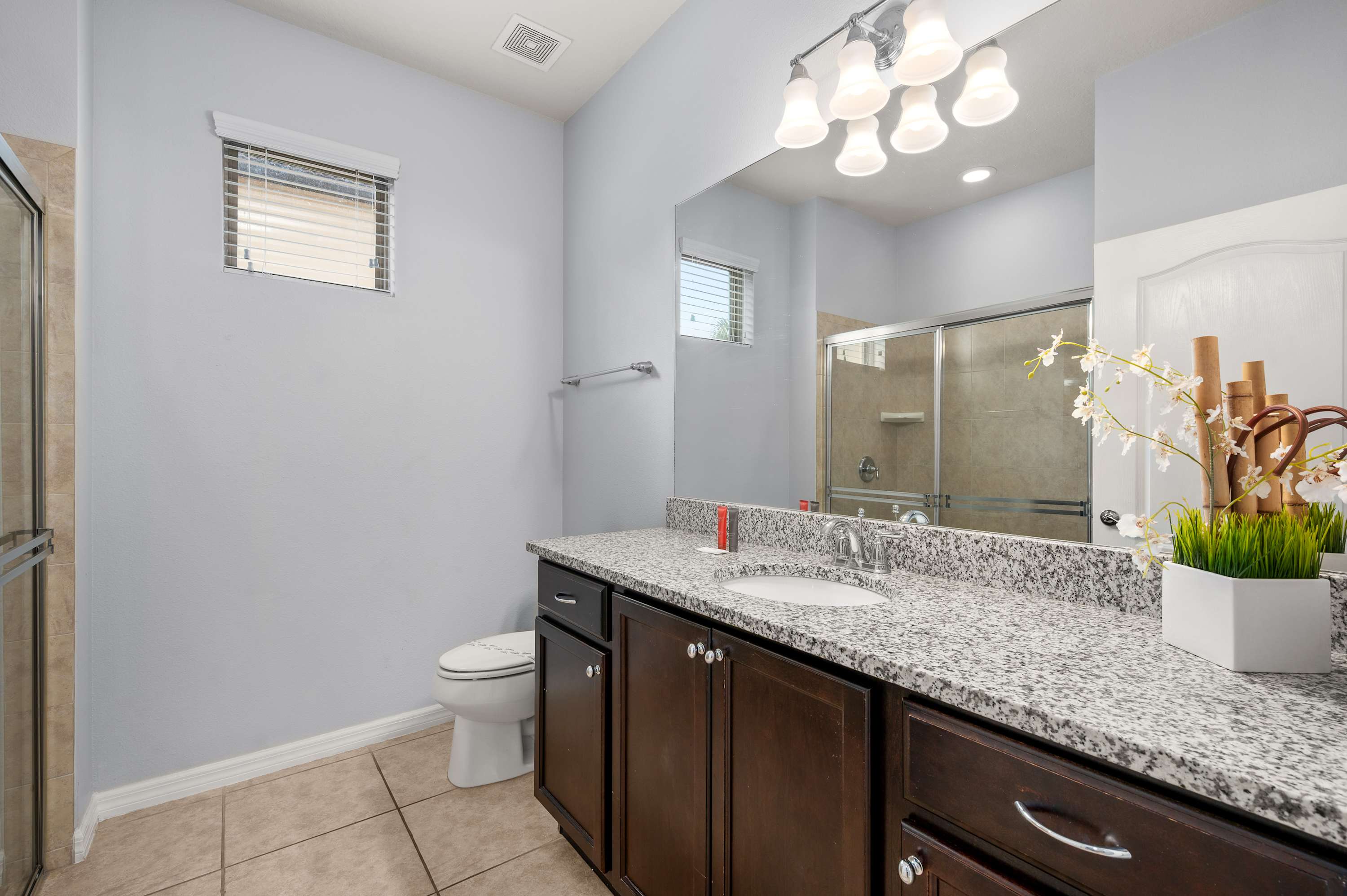 Bathroom w/ stone-top vanity, sink & warm lighting — fresh & functional.