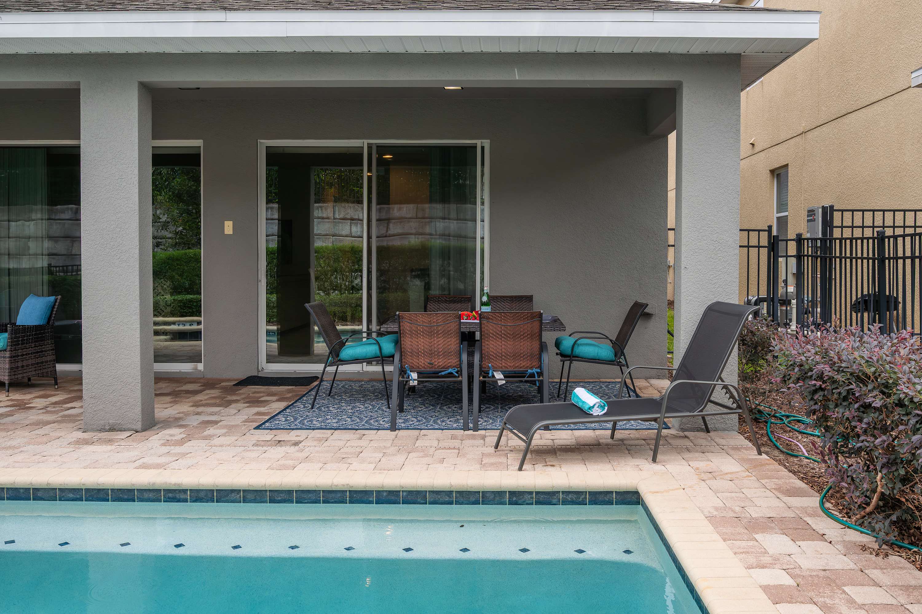 Covered patio dining area with poolside lounge chairs for relaxing.