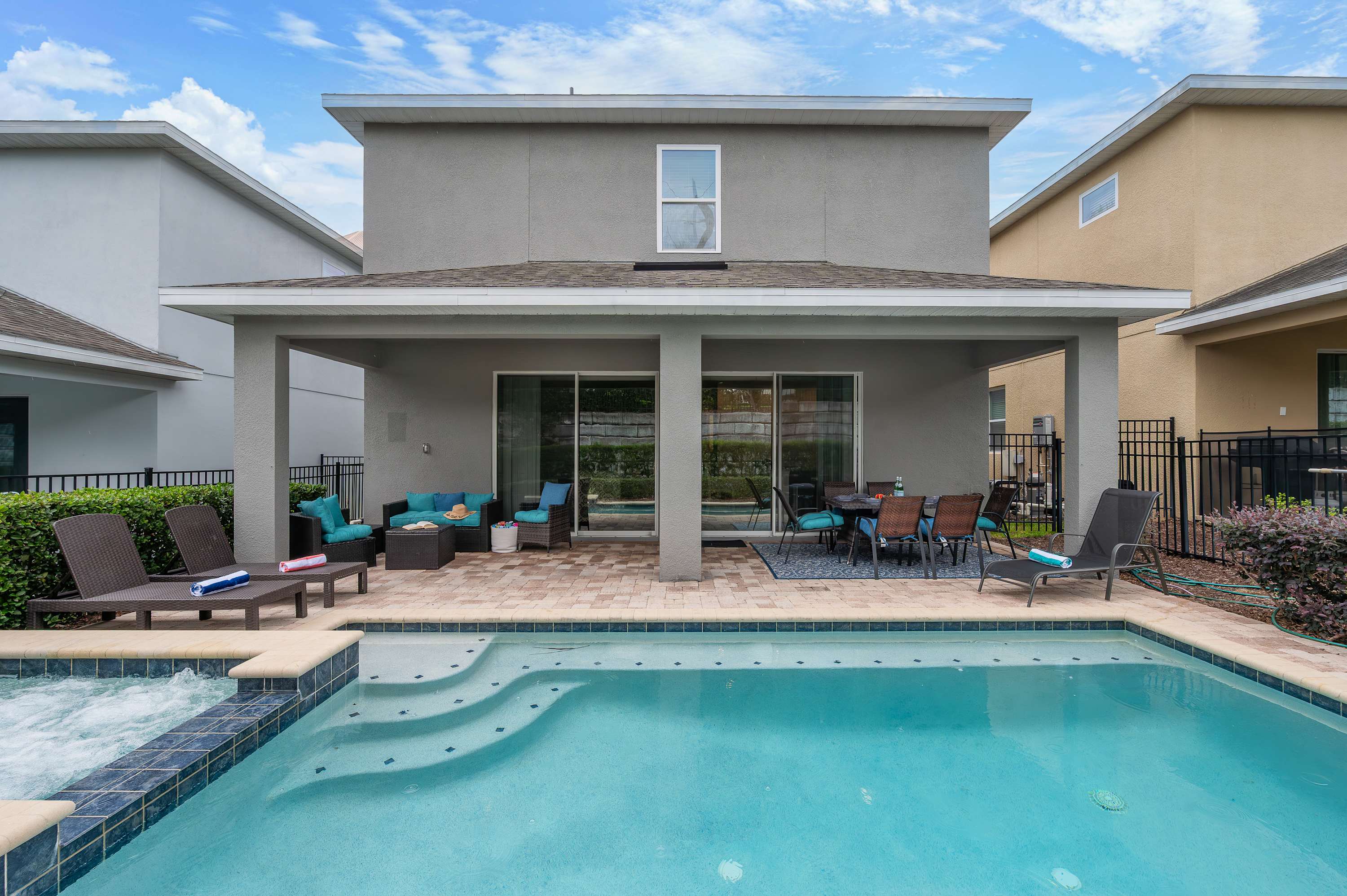 Covered patio with seating and a pool with spa for relaxing outdoor enjoyment