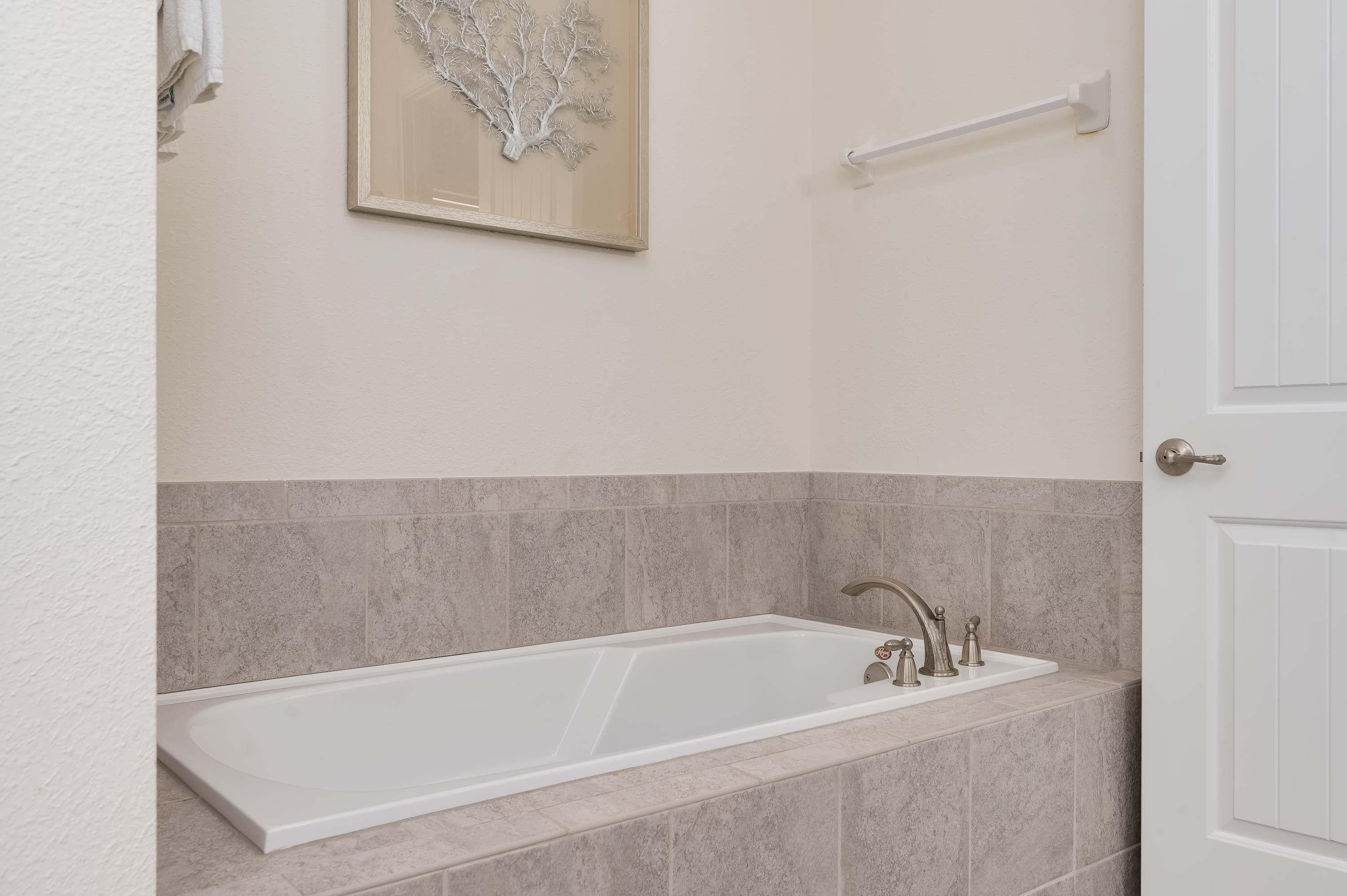 Relax in the spacious bathtub surrounded by neutral tile accents.