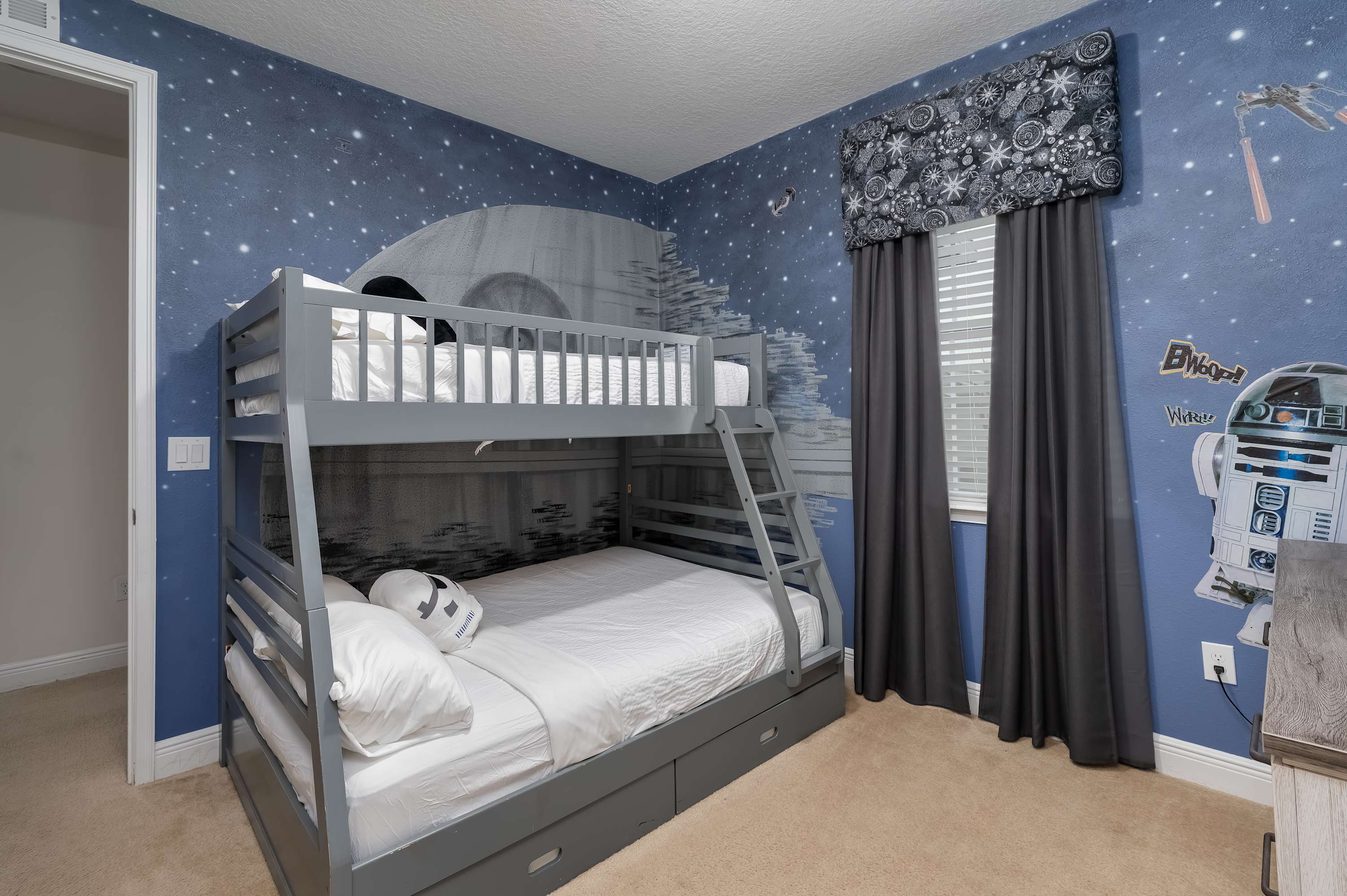 Space-themed kids' bedroom with bunk beds and starry wall murals.