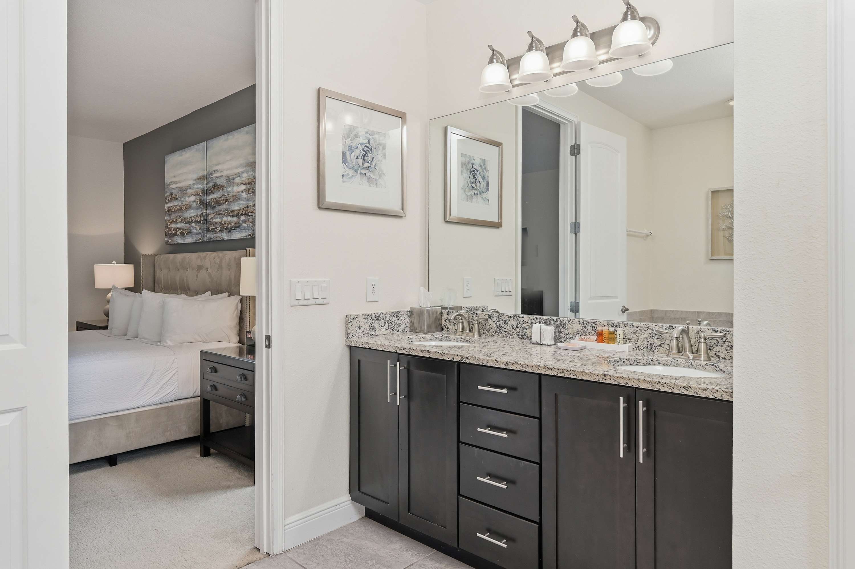 Modern bathroom with granite countertops and dual sinks adjacent to the bedroom