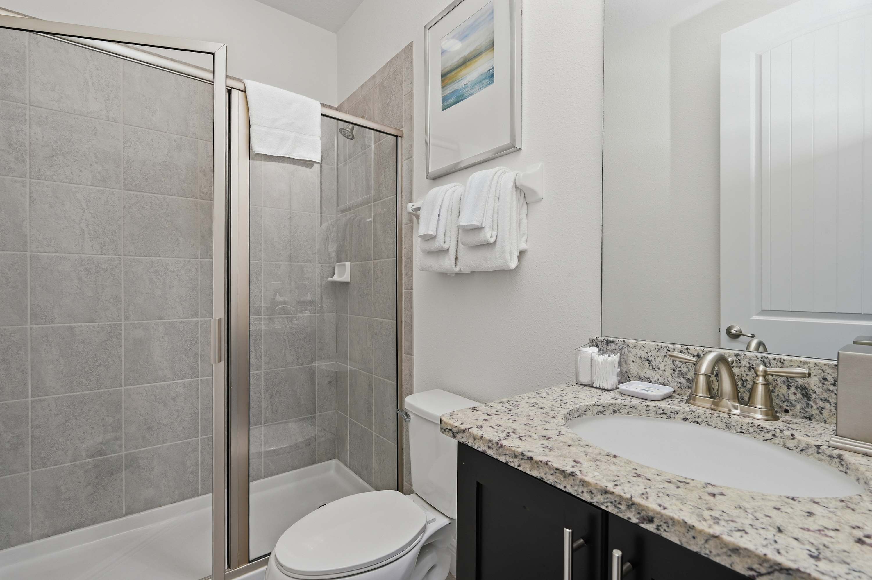 Modern bathroom featuring a glass-enclosed shower and granite countertop.
