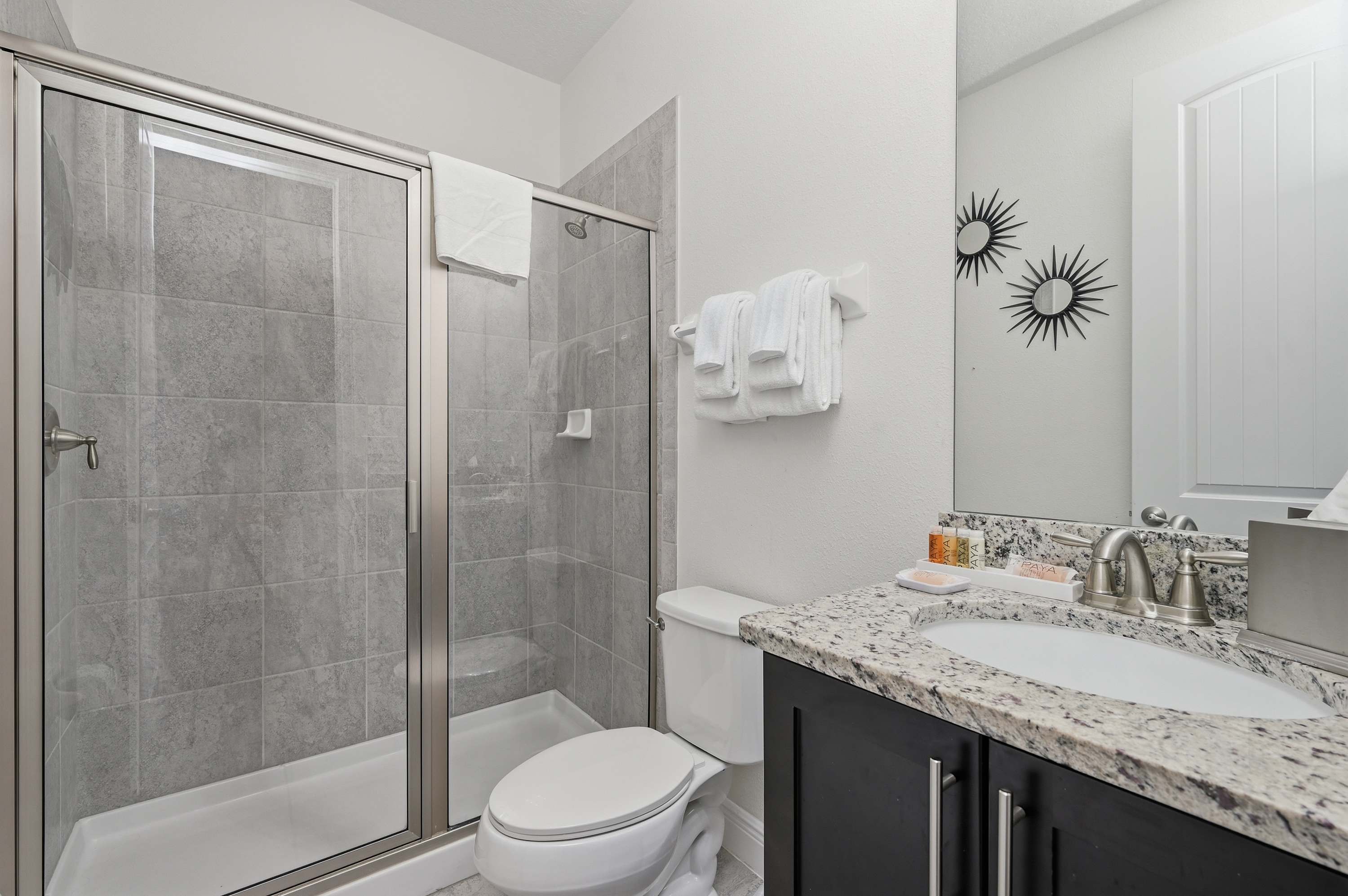 Modern bathroom featuring a glass-enclosed tiled shower and granite countertop vanity.