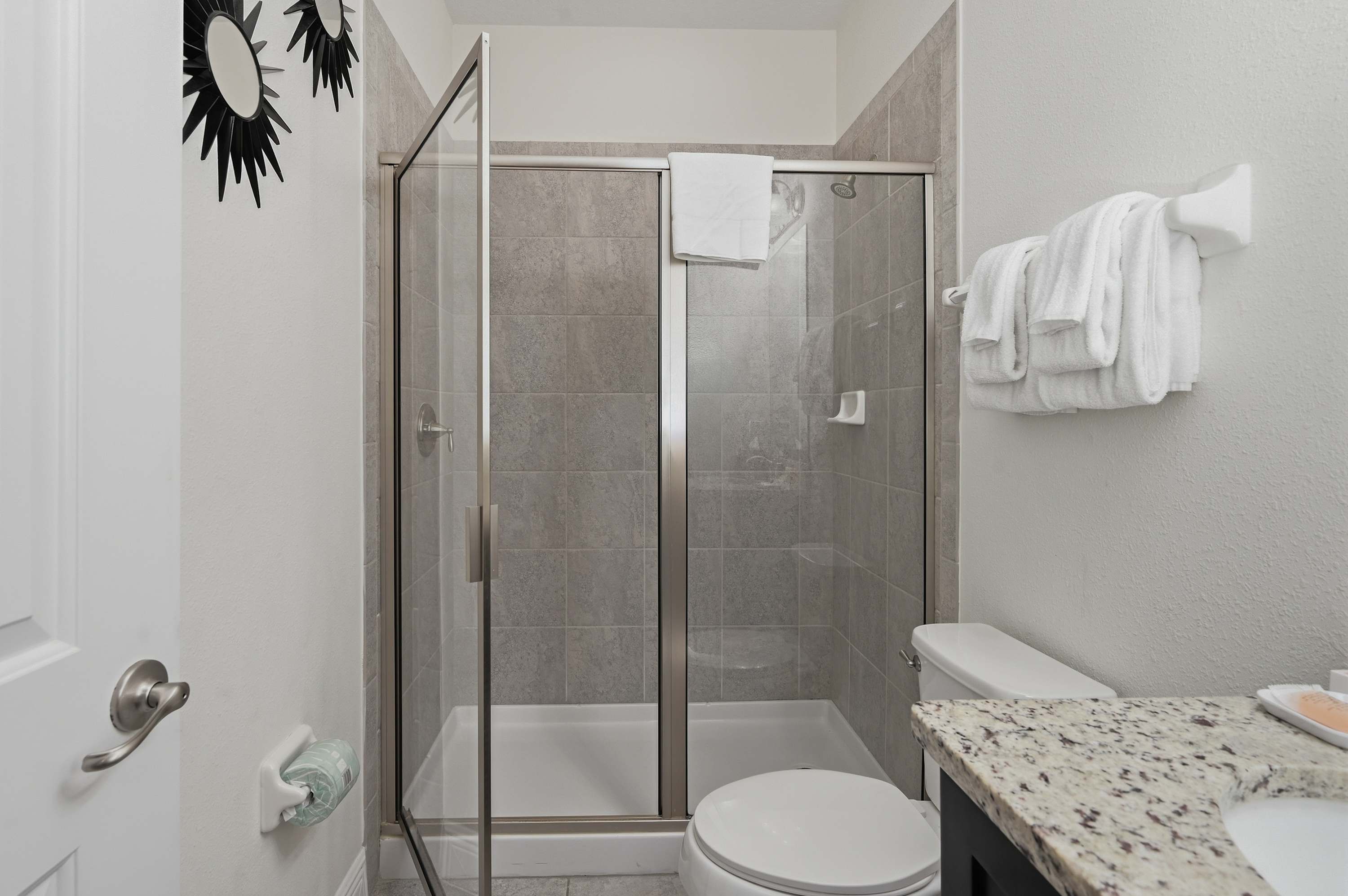 Modern bathroom featuring a glass-enclosed shower and granite countertop.