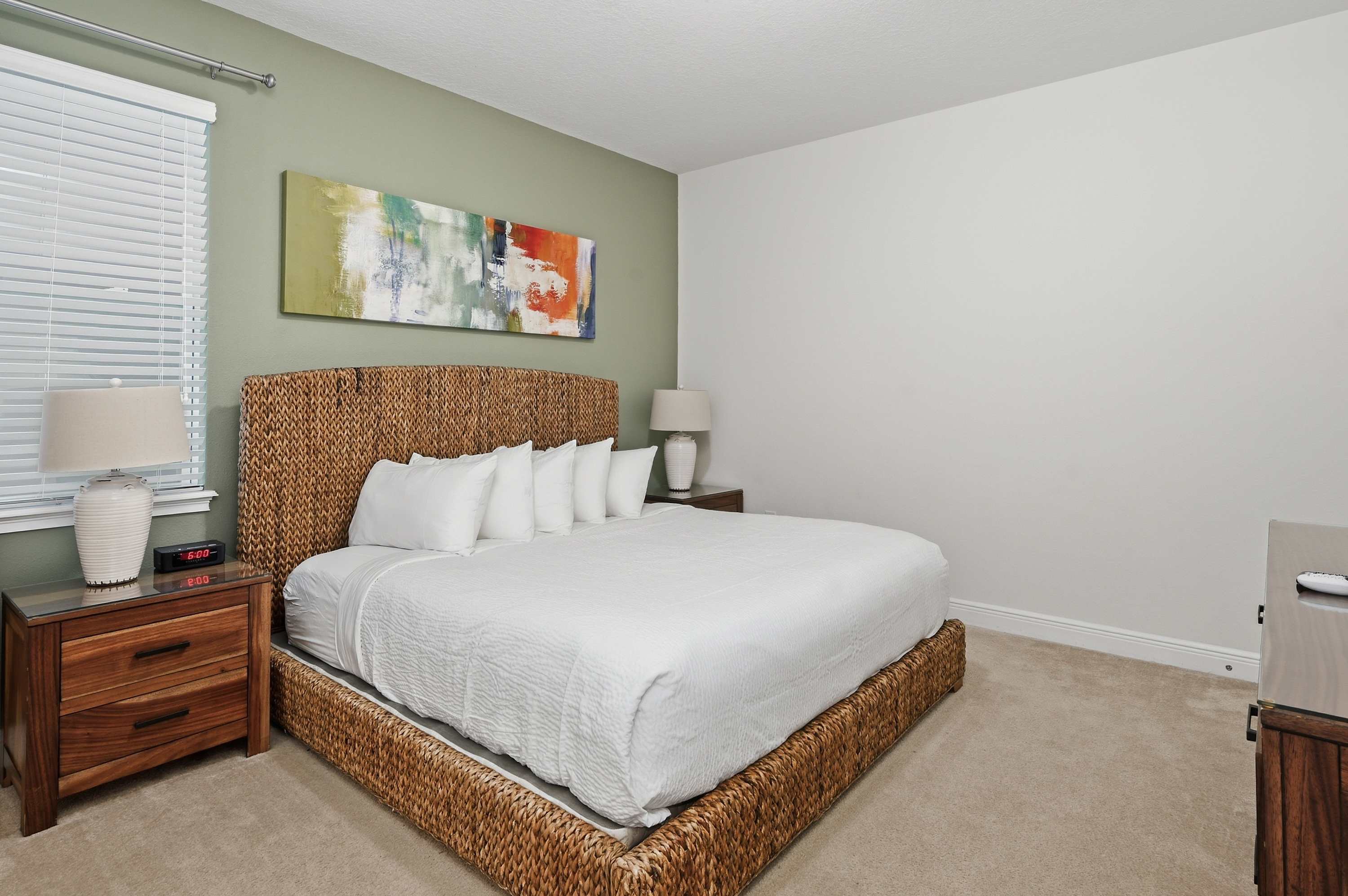 King-size bed with a woven frame and modern abstract art in a serene bedroom.