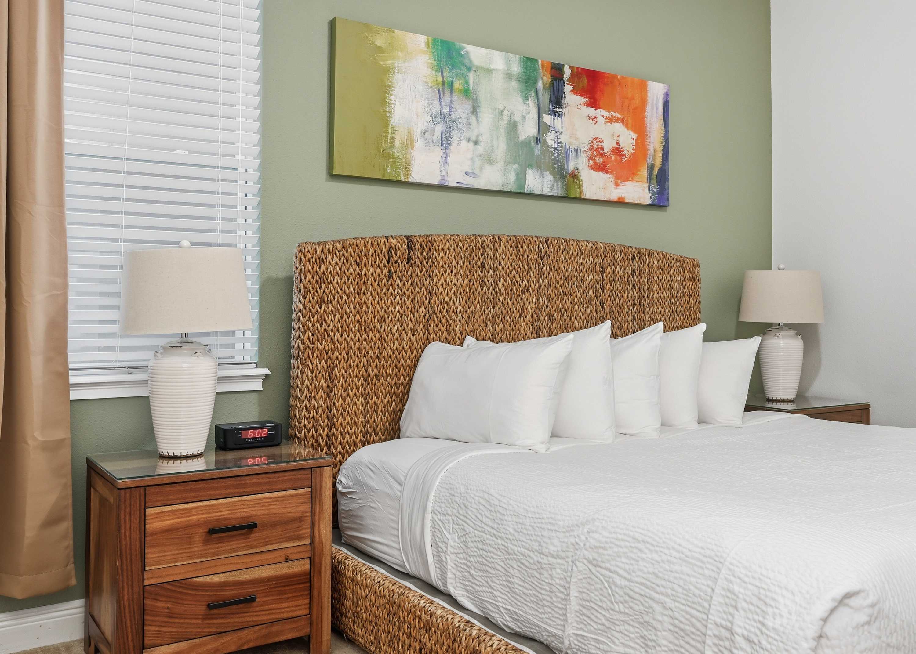 King bed with woven headboard and modern abstract art in a softly colored room