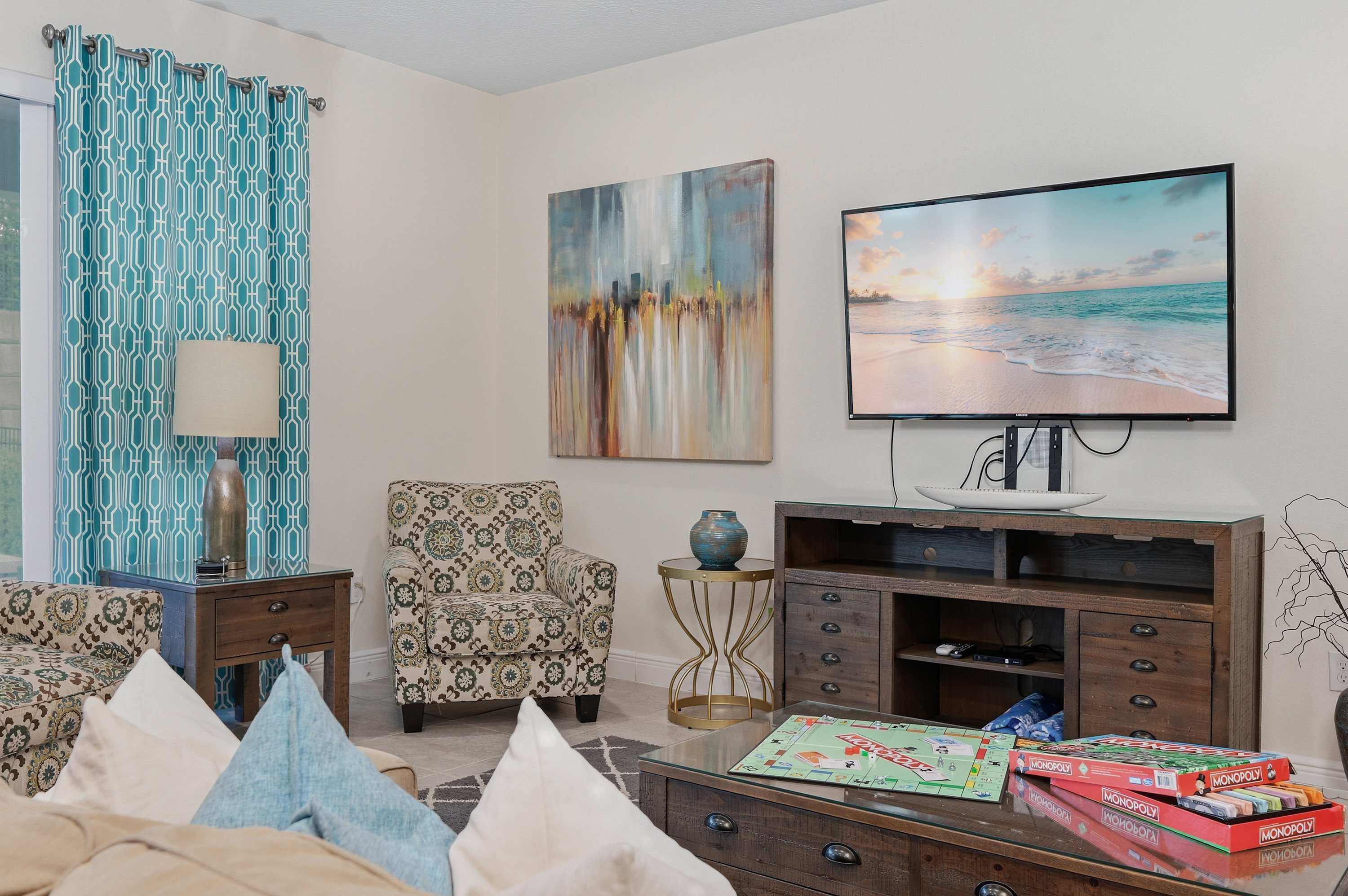 Relax in the cozy living room featuring patterned armchairs and a large flat-screen TV.