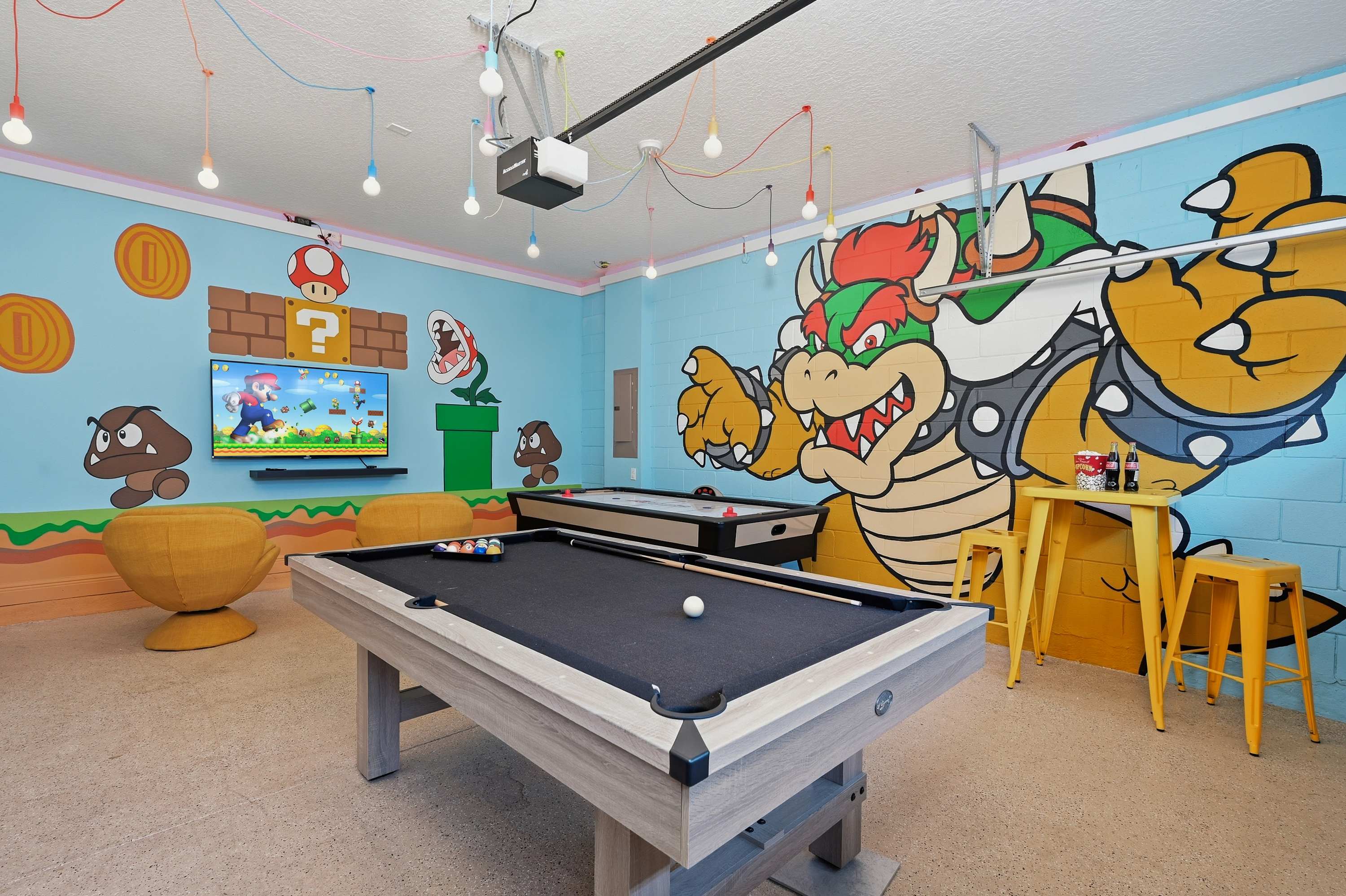 Game room featuring a pool table, air hockey, and Super Mario-themed wall art for family-friendly fun.