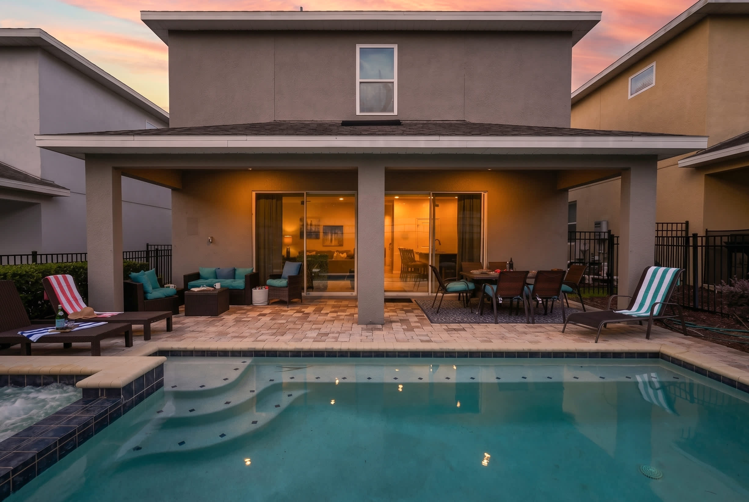 Modern backyard patio with pool and outdoor seating area at sunset
