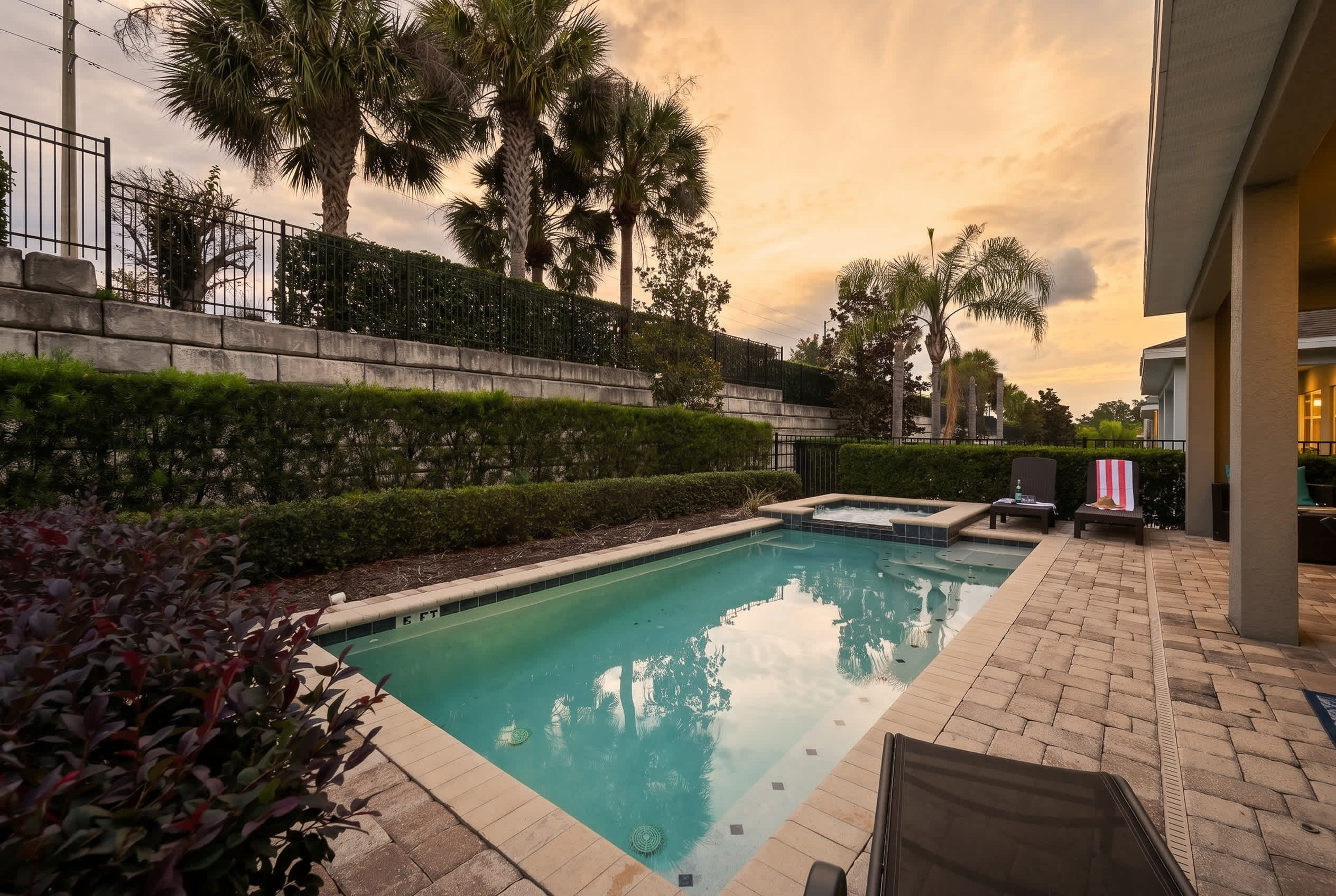 Relax by the private pool and spa area surrounded by lush greenery at sunset.