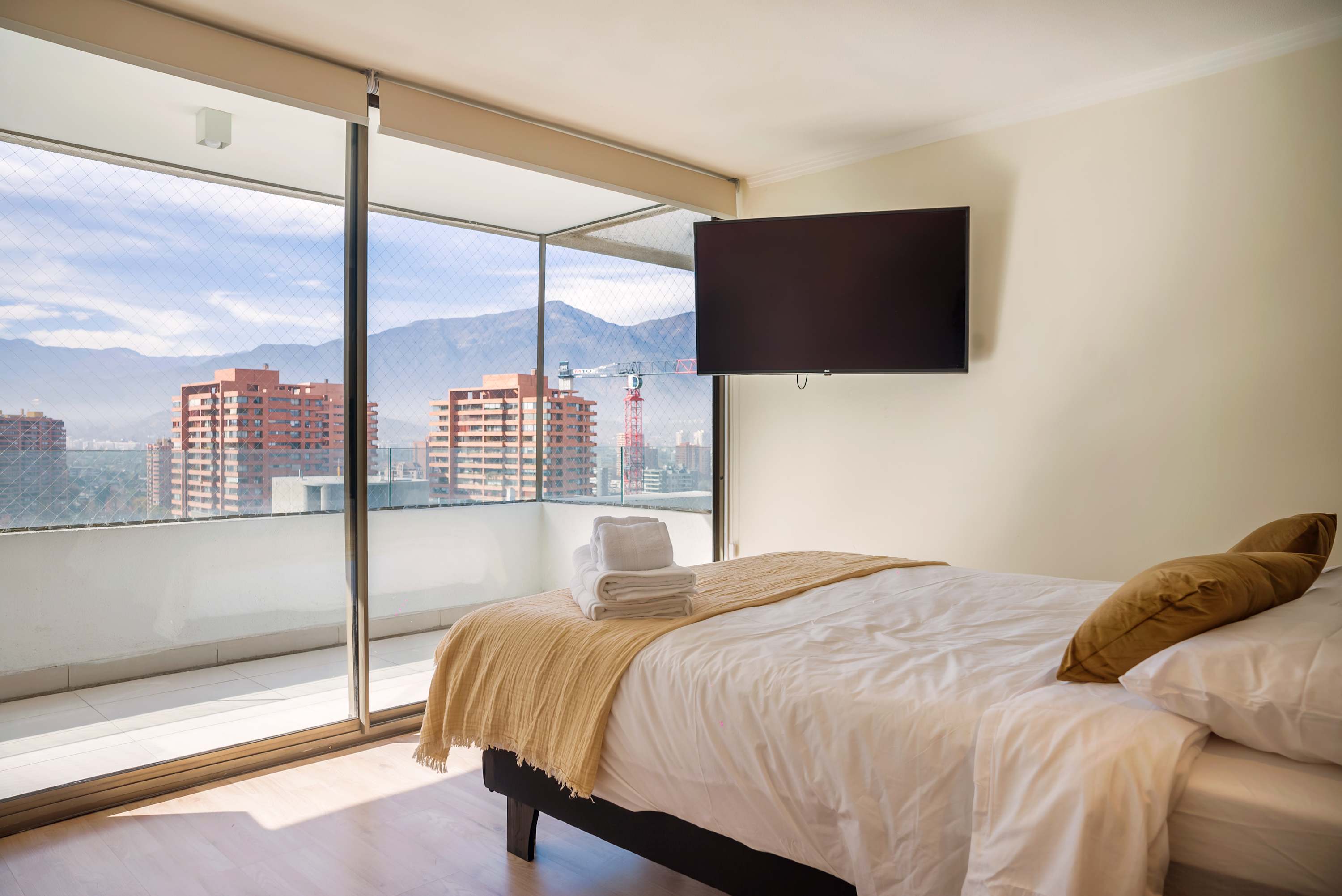 Relax in a cozy bedroom with stunning city and mountain views from your private balcony.