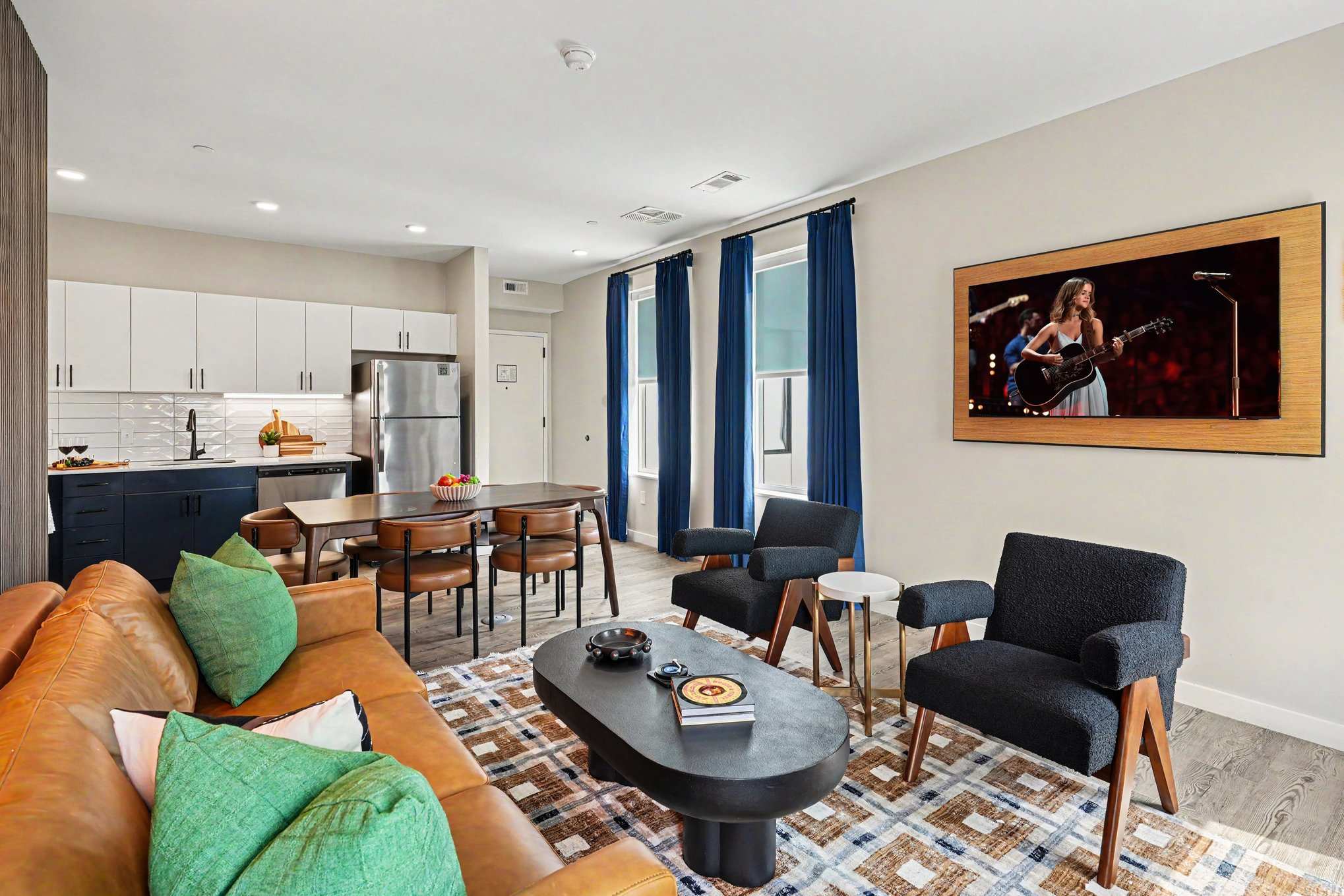 Bright and open living area featuring a smart TV and plush furnishings. Connects to the dining area and kitchen.