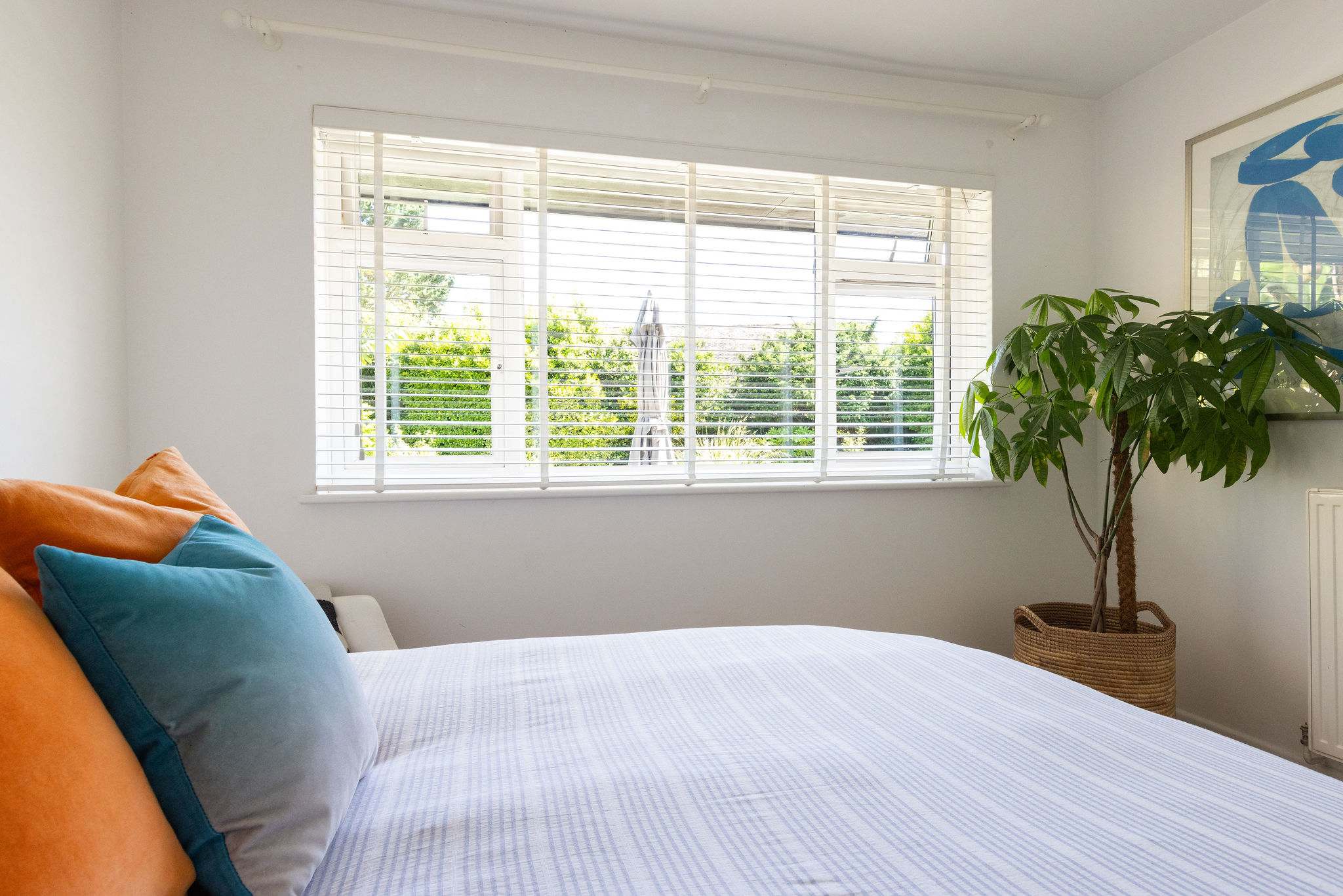 Garden views and soft colours create a relaxed bedroom feel