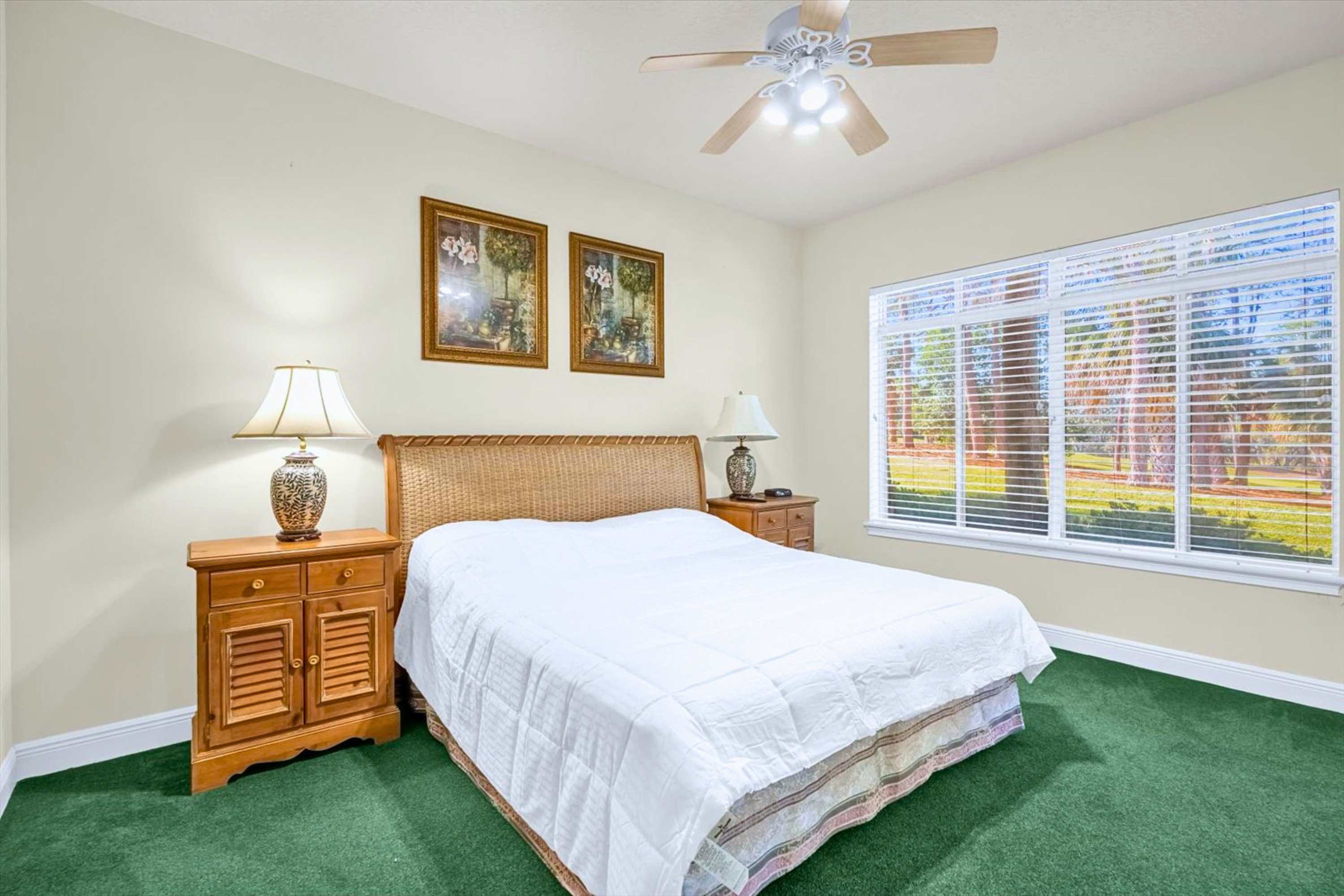 Peaceful bedroom featuring a queen bed with soft lighting from a bedside lamp and a ceiling fan for added comfort and airflow