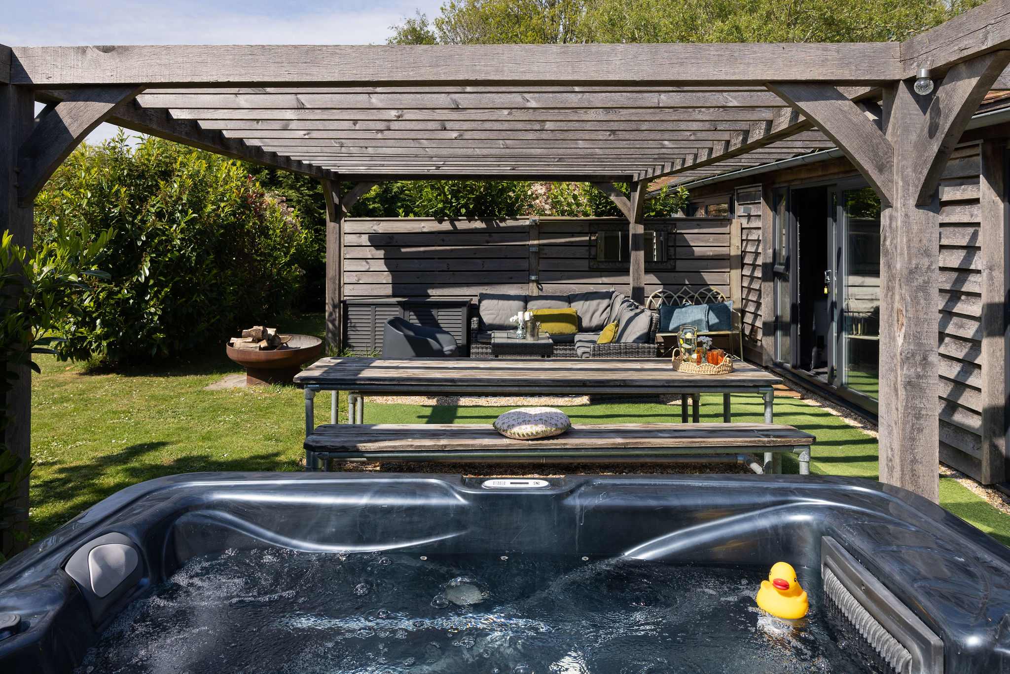Indulge in countryside relaxation with a private hot tub and spacious outdoor lounge area.