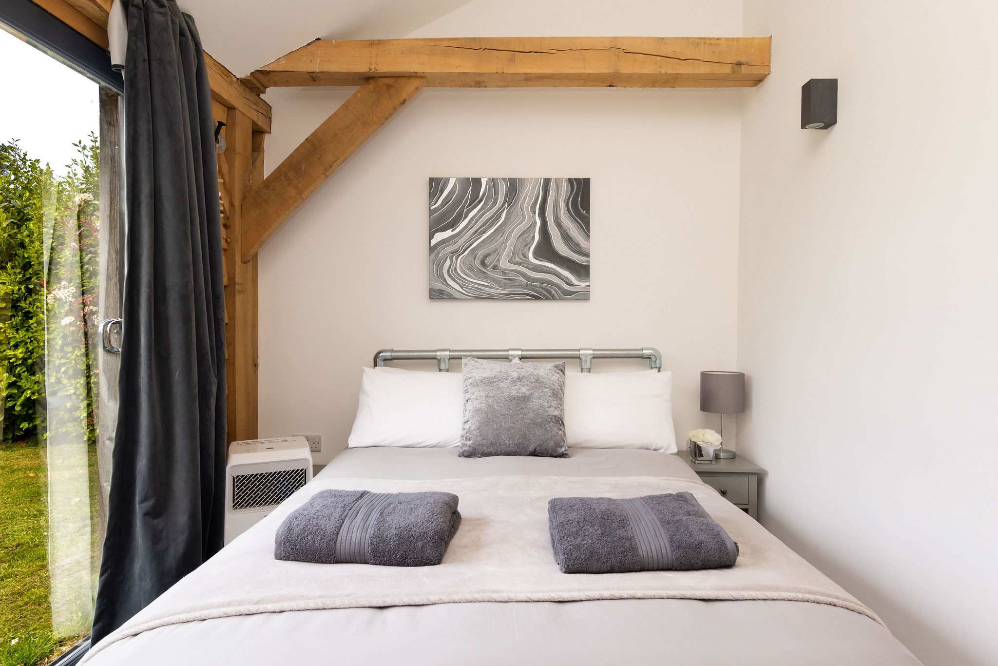 Wake up to nature in this serene double bedroom featuring beautiful exposed wooden beams.