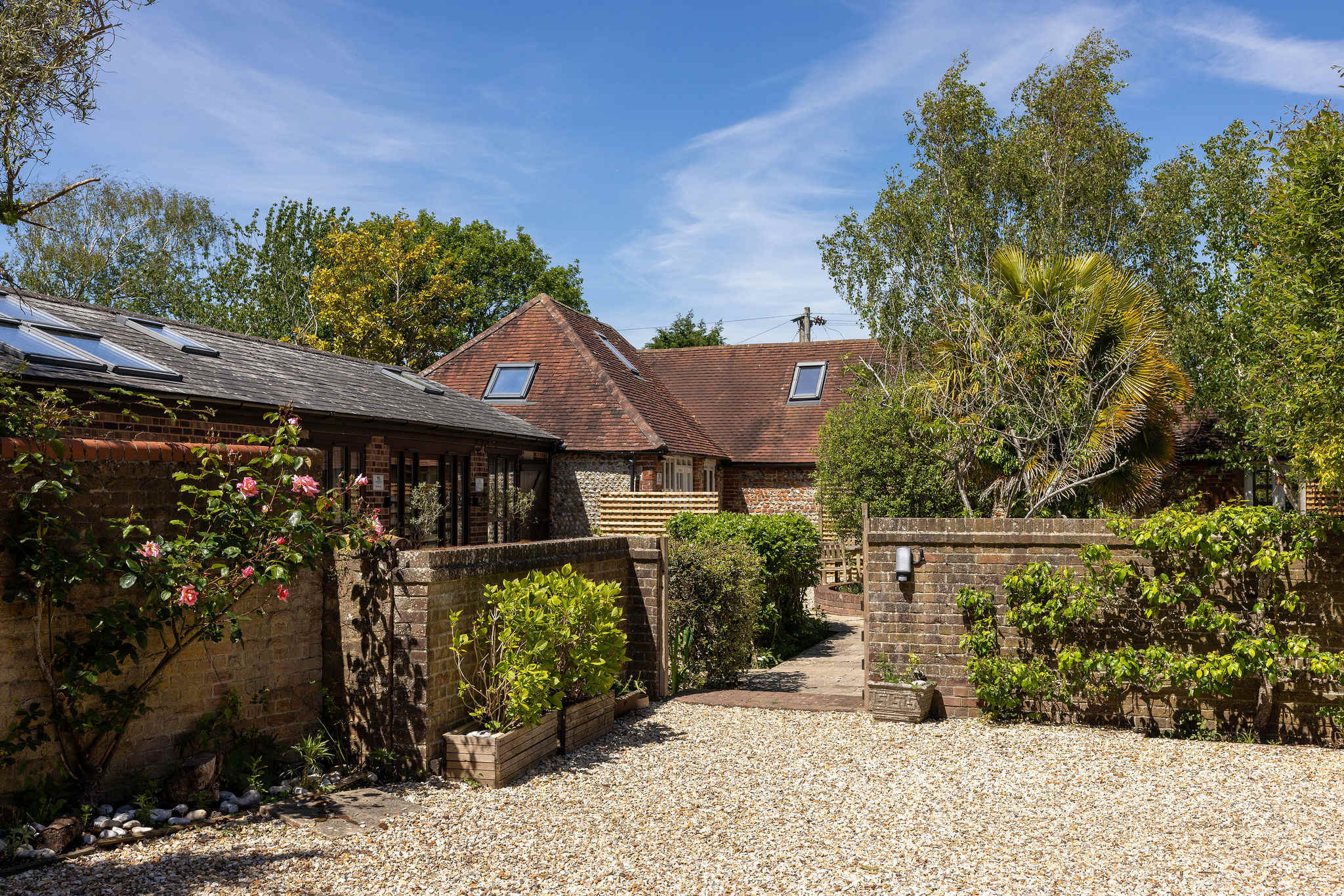 Pretty courtyard surroundings, with roses, trees and mature shrubs.