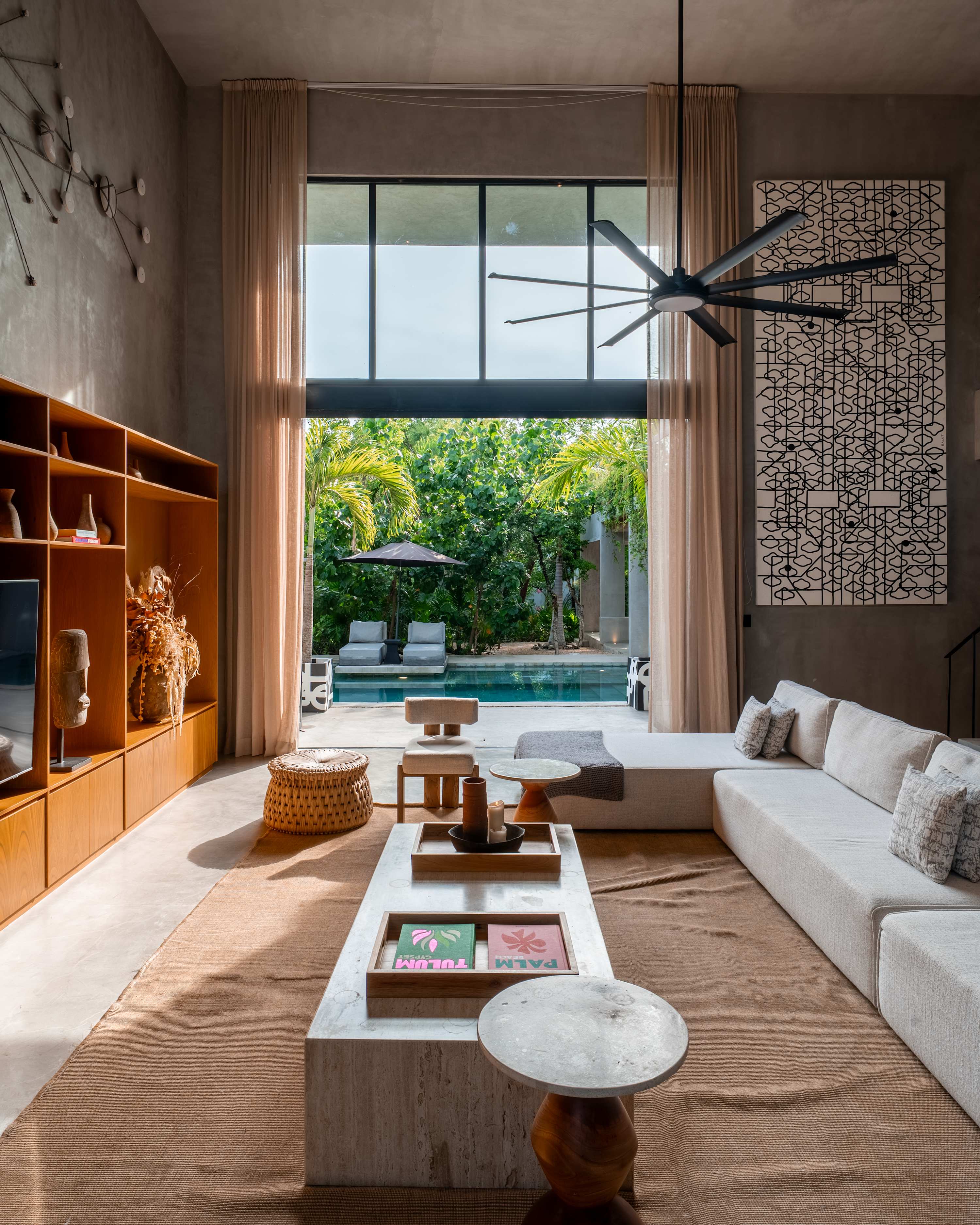 Elegant living room with striking brutalist architecture and soaring high ceilings for a sophisticated, modern vibe with pool view.