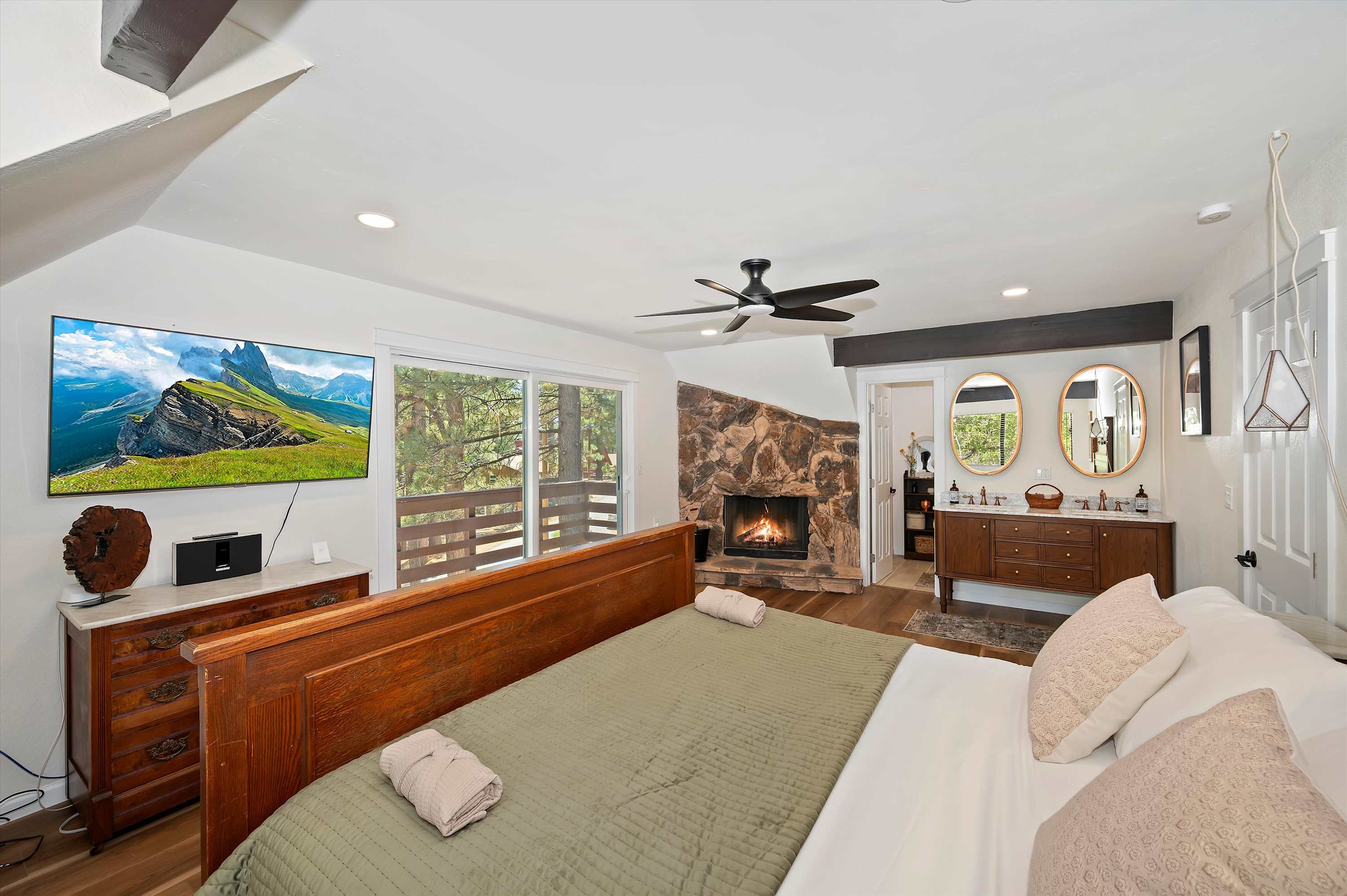 The primary California king suite boasts a smart TV, balcony, fireplace, & ensuite​