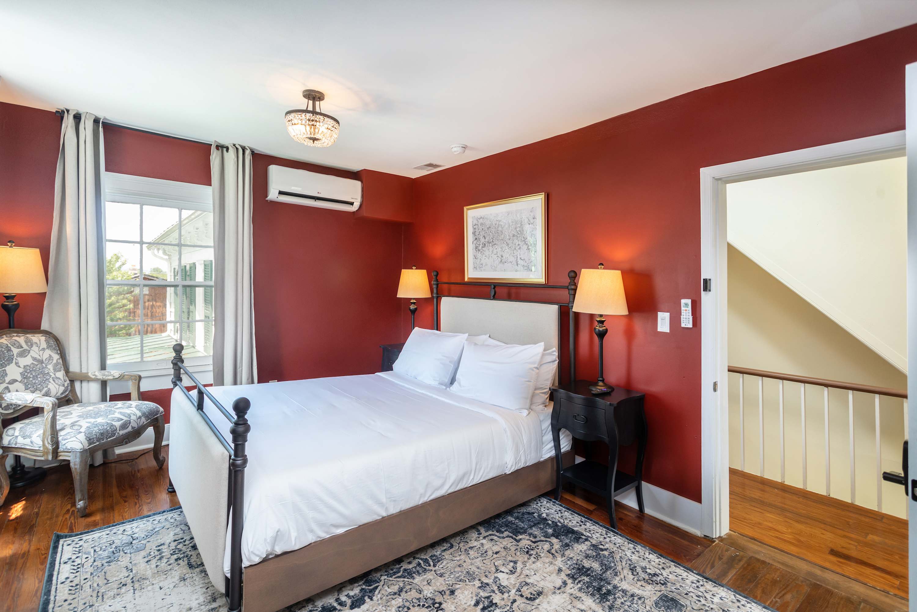 Cozy bedroom with red walls, a comfortable bed, and natural light from the window.