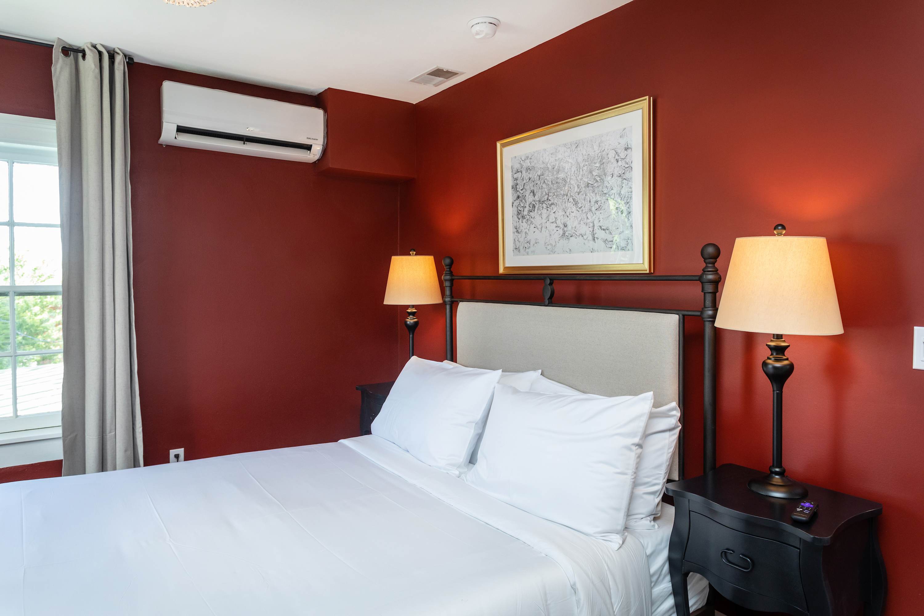 Cozy bedroom featuring a metal bed frame, warm red walls, and soft lighting from bedside lamps.