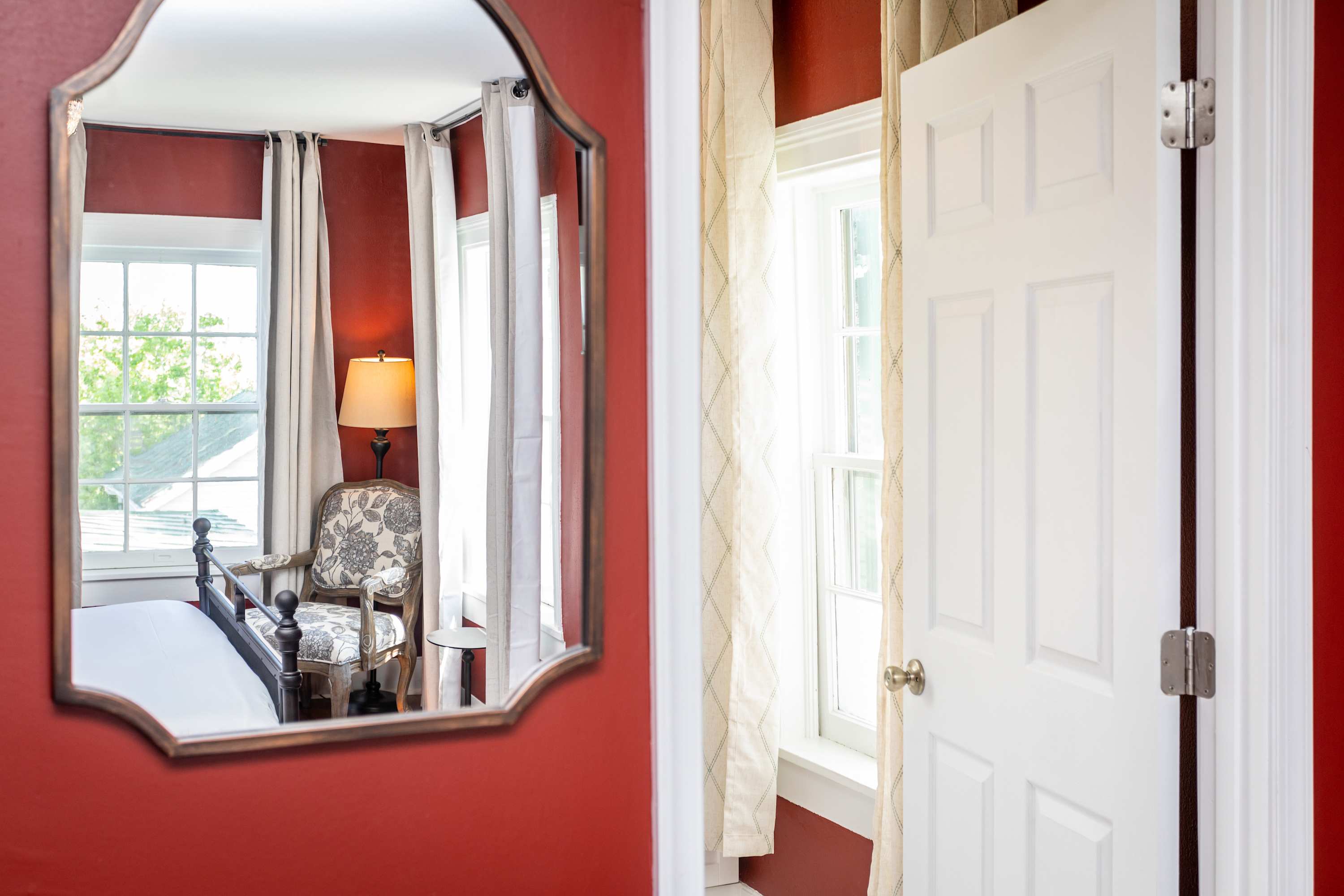 A cozy corner with a floral armchair and soft lighting reflected in a vintage mirror.