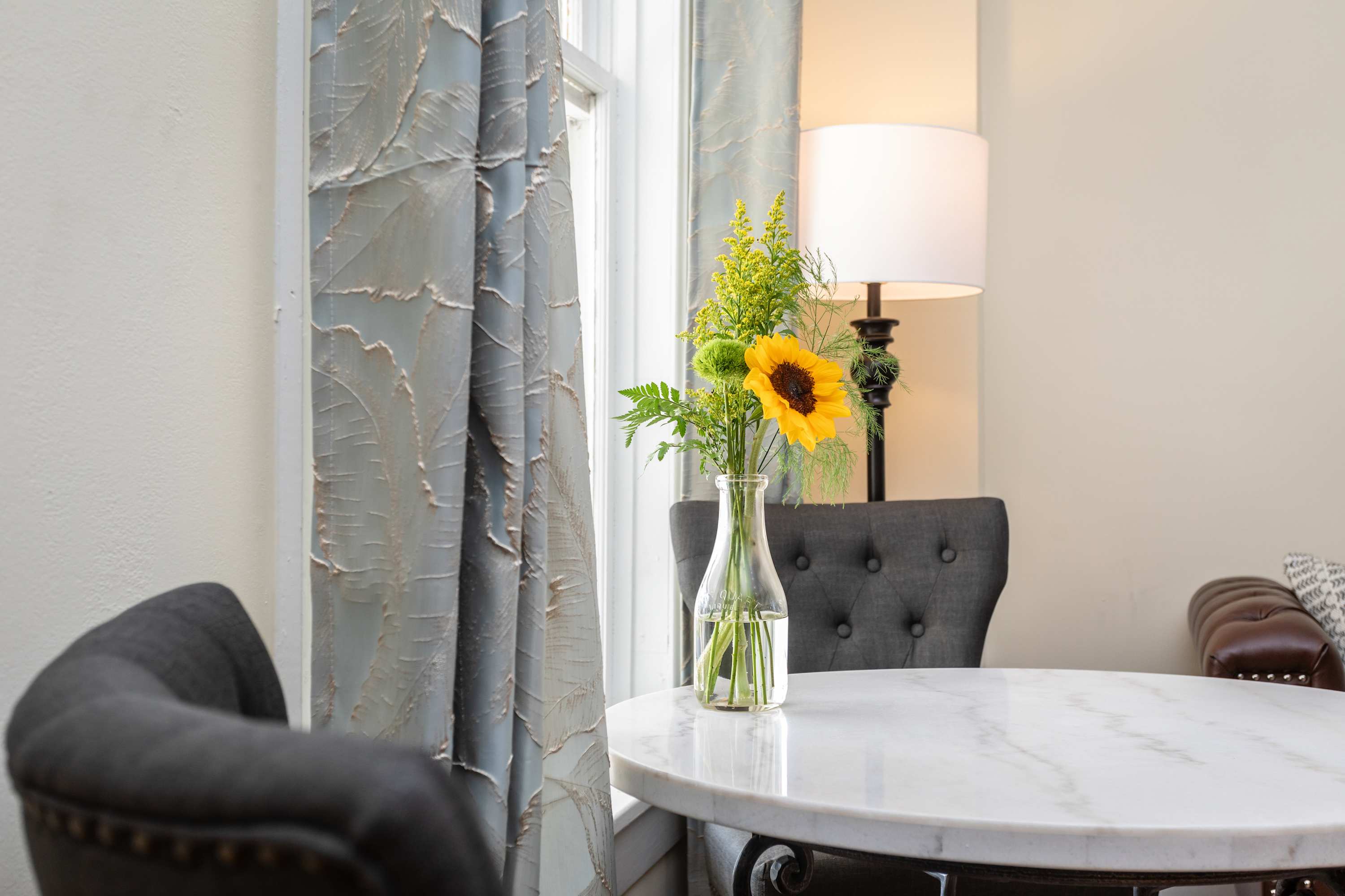 Sunlight brightens the marble table with a fresh floral arrangement in a cozy seating area.