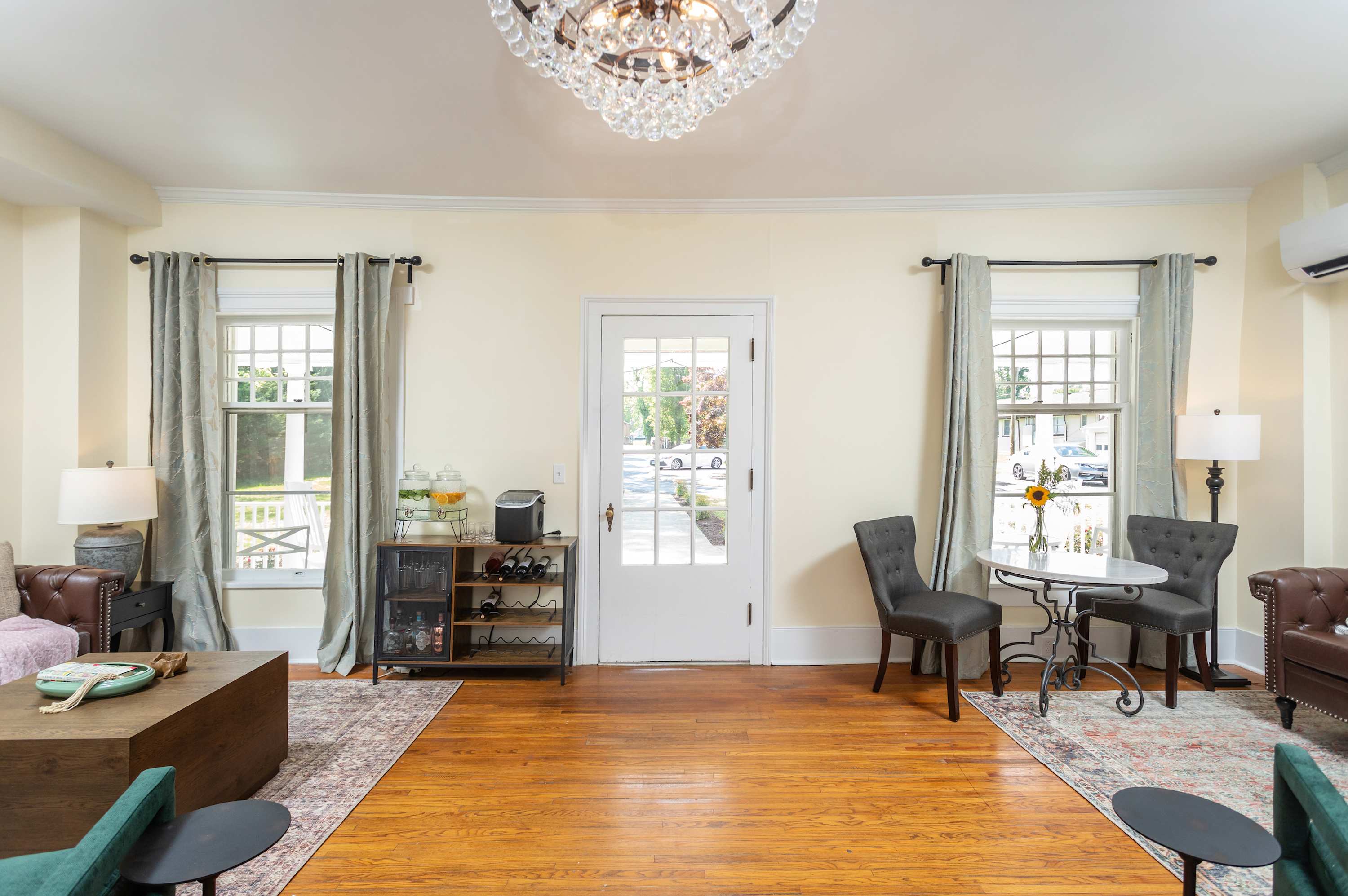 Living area with natural light, hardwood floors, and a crystal chandelier