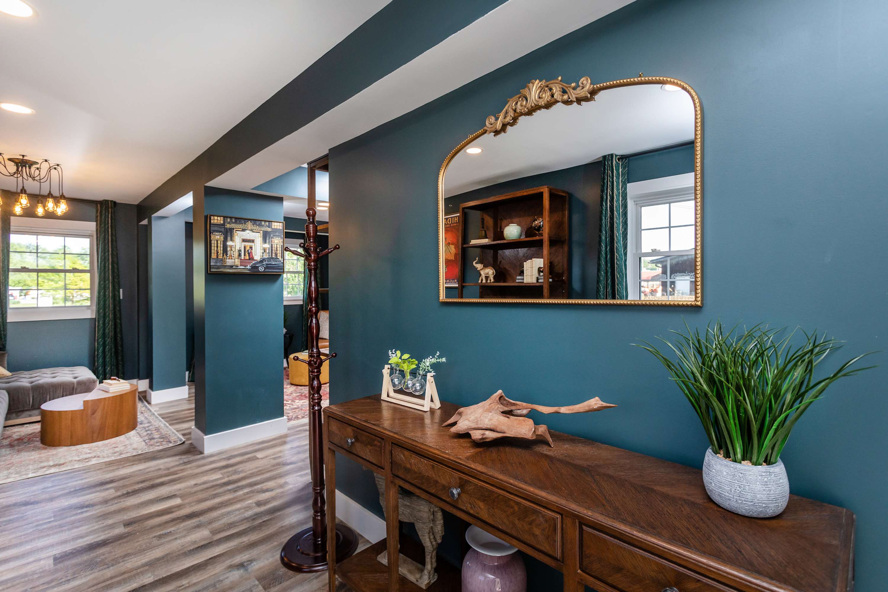 Entryway with a vintage wooden console table and ornate mirror against teal walls