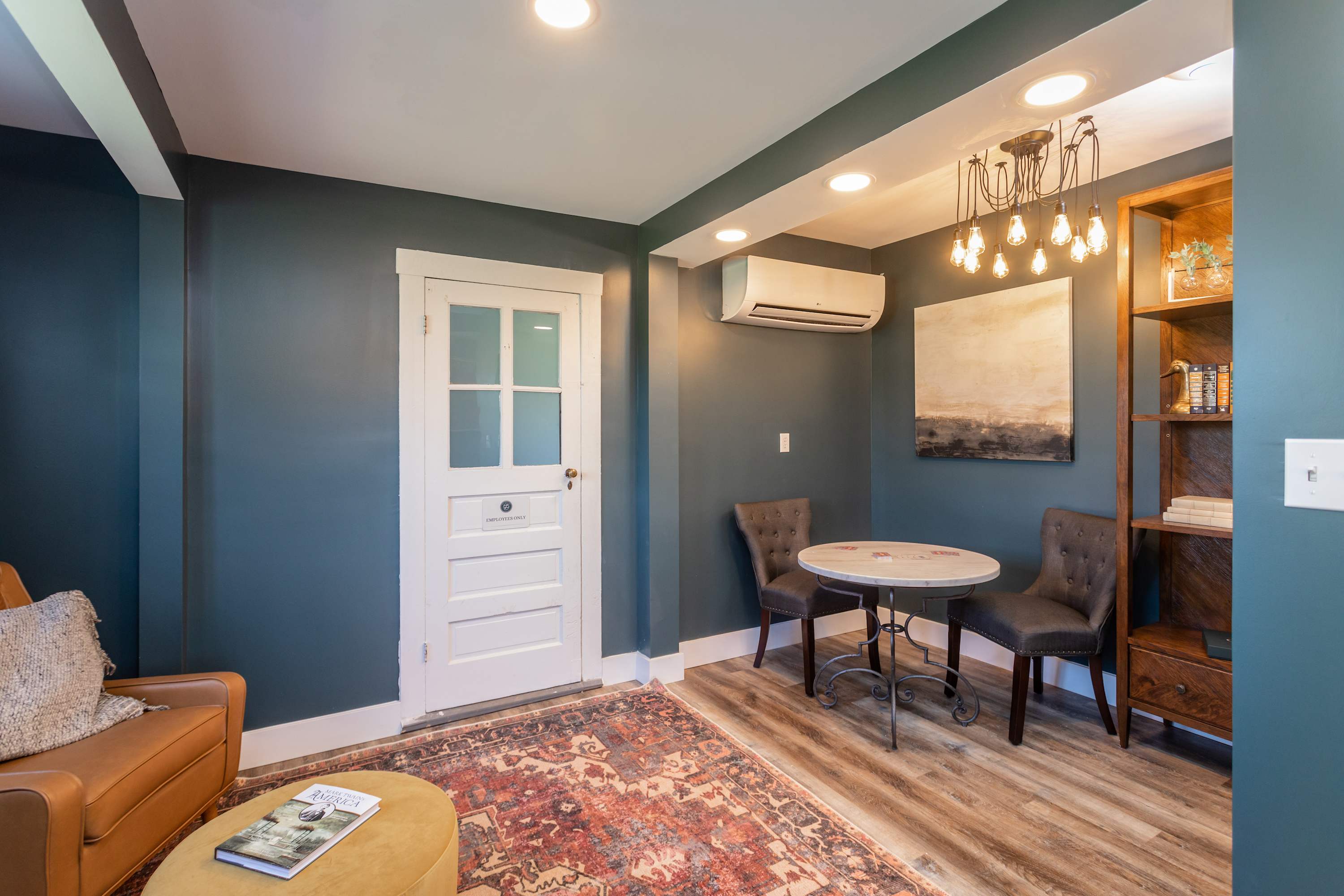 Cozy seating area with a round table, tufted chairs, and warm lighting in a modern room.