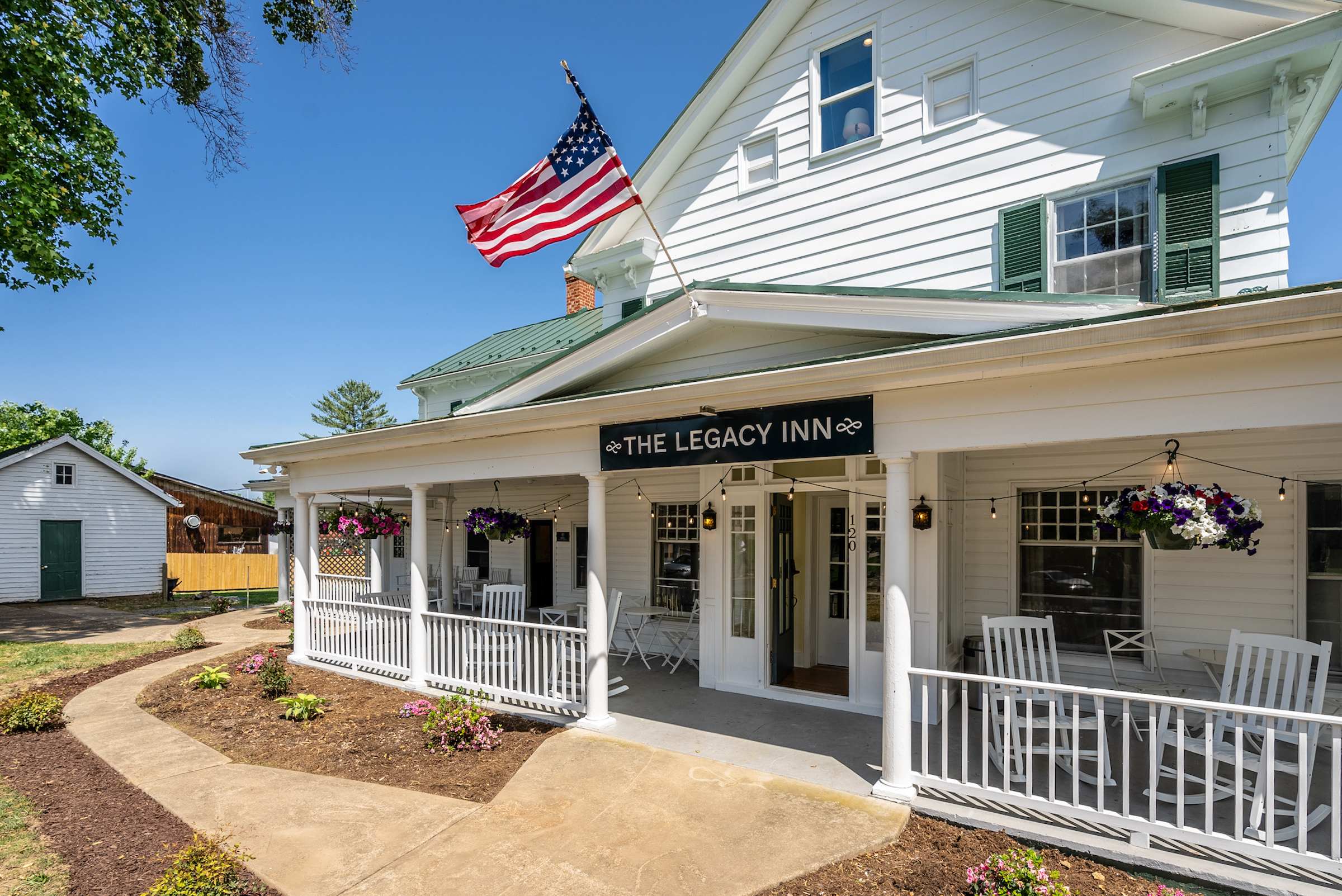 Front porch of the legacy inn with rocking chairs and hanging flower baskets