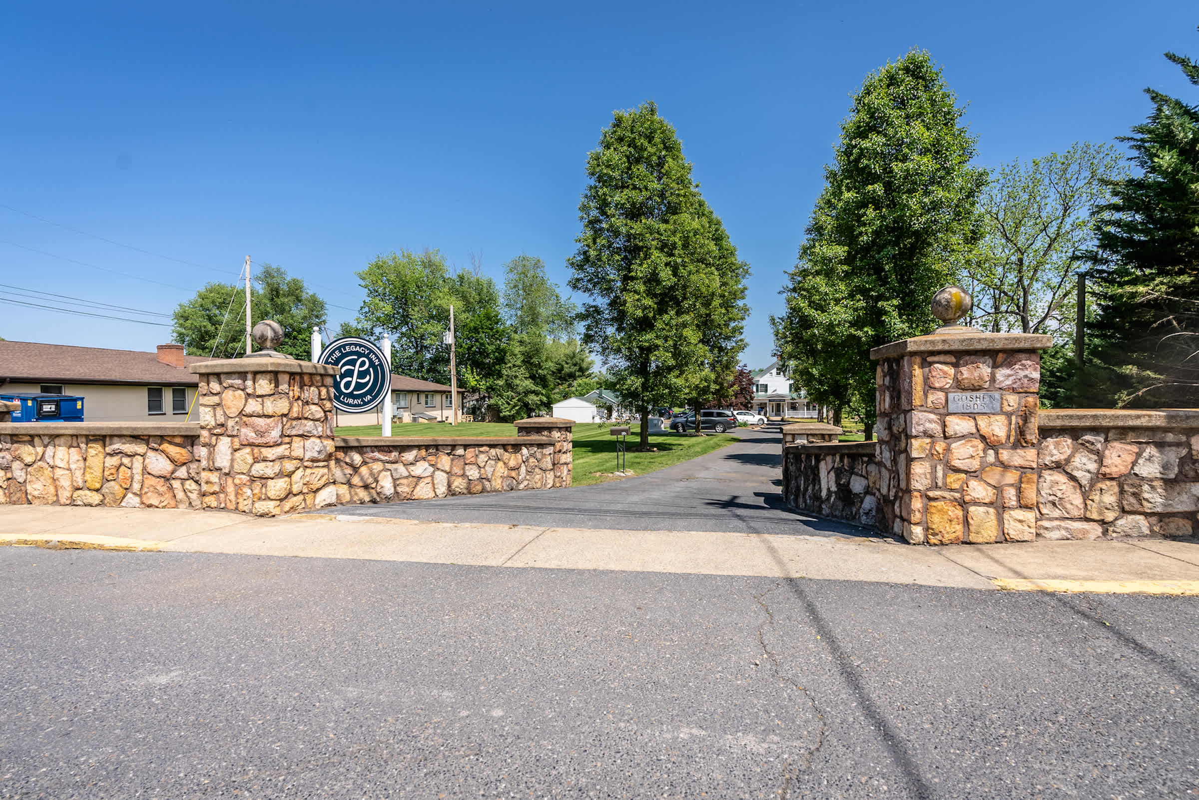 Entrance to the legacy inn featuring stone pillars and a tree-lined driveway.
