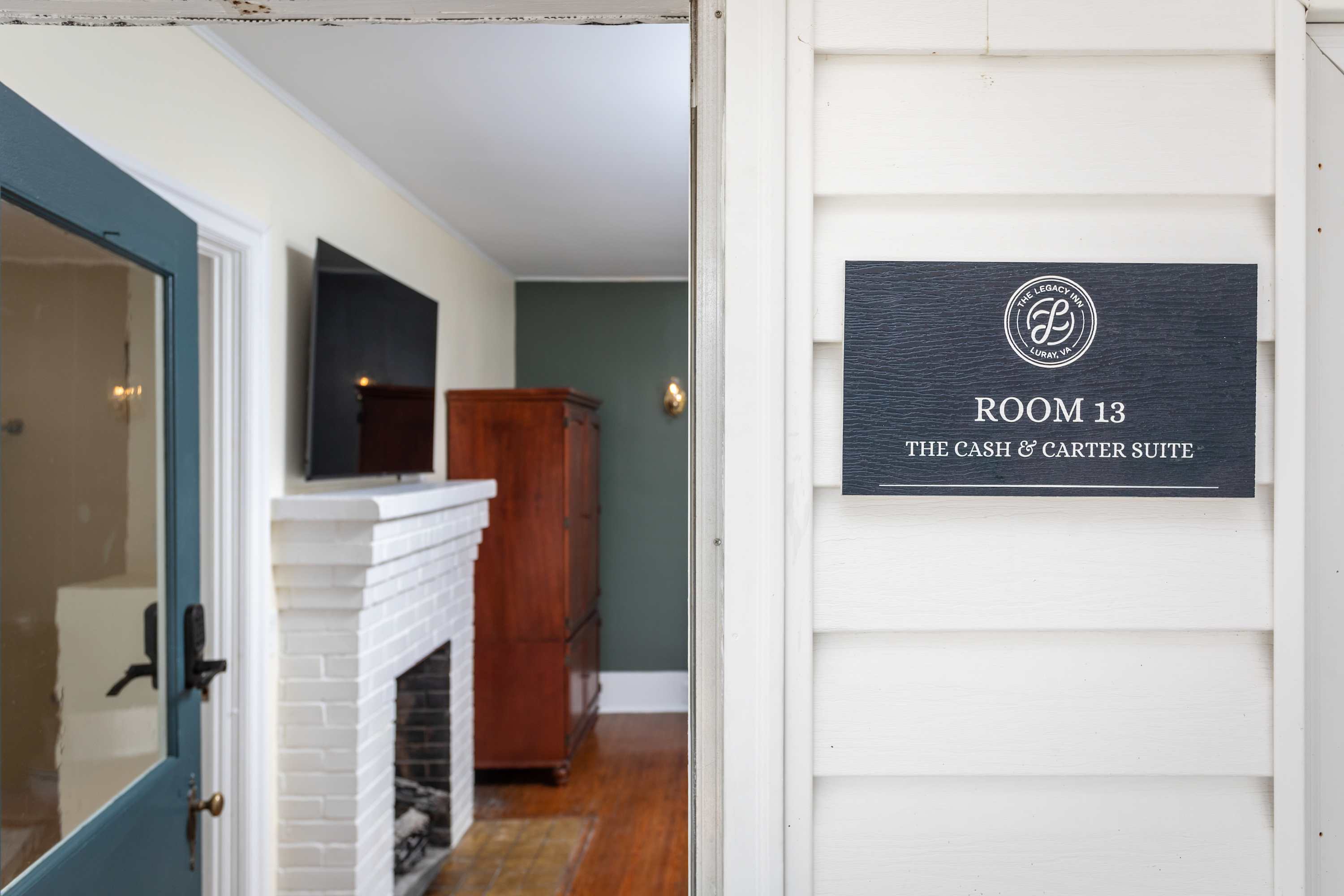 Entrance to room 13, the cash & carter suite, featuring a white brick fireplace and wooden furniture.