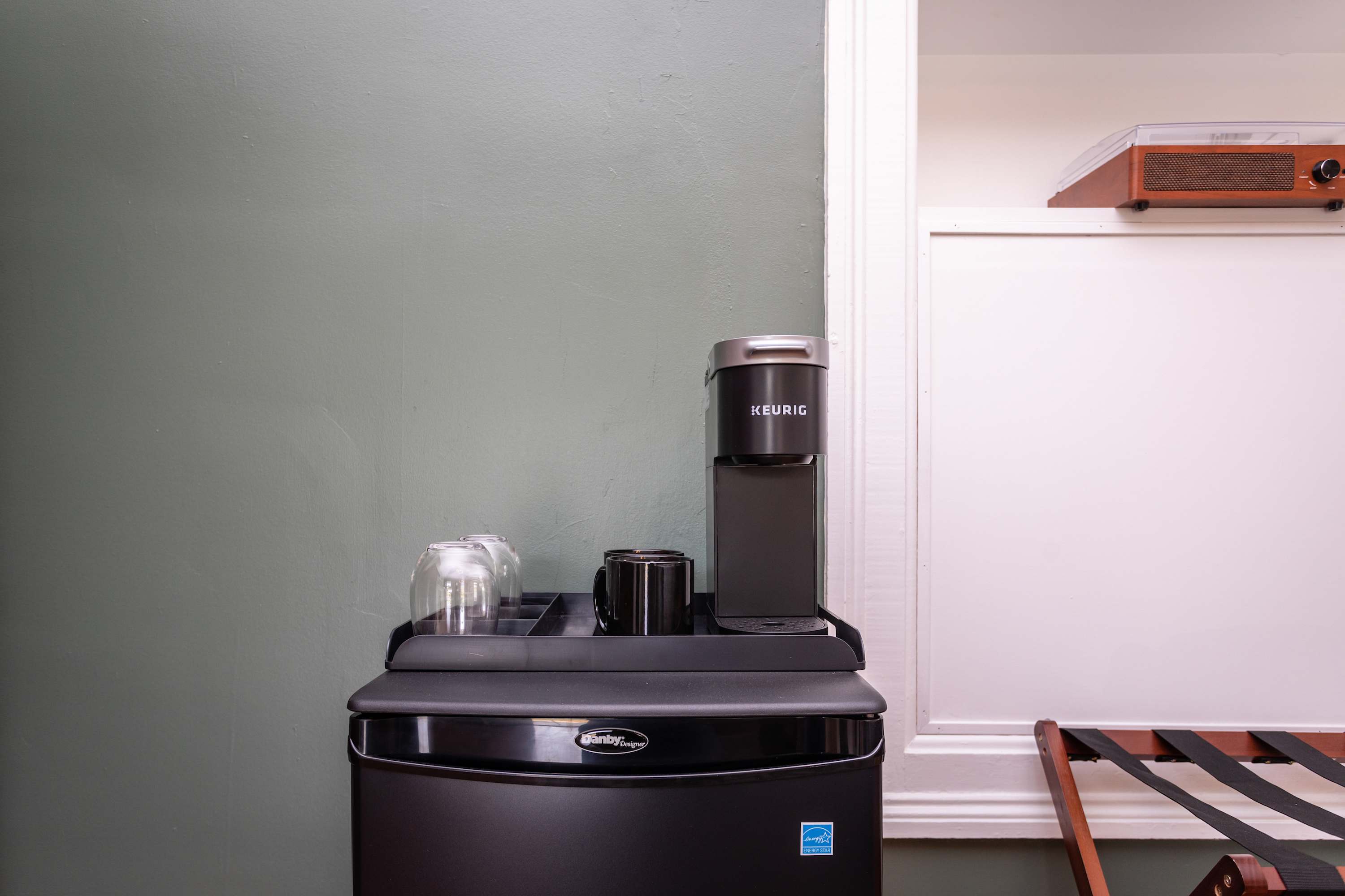 Compact coffee station with a keurig machine and glassware for convenient brewing.
