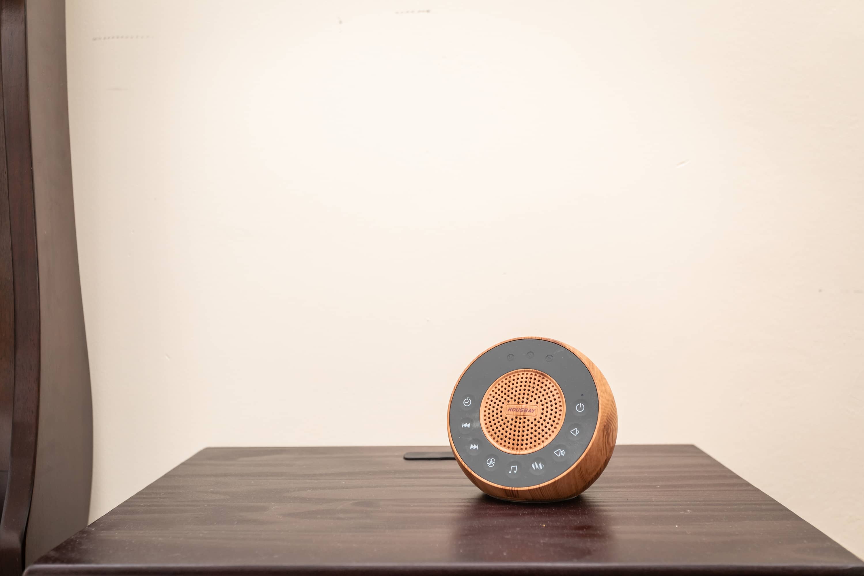 Compact wooden speaker with touch controls on a dark wood table