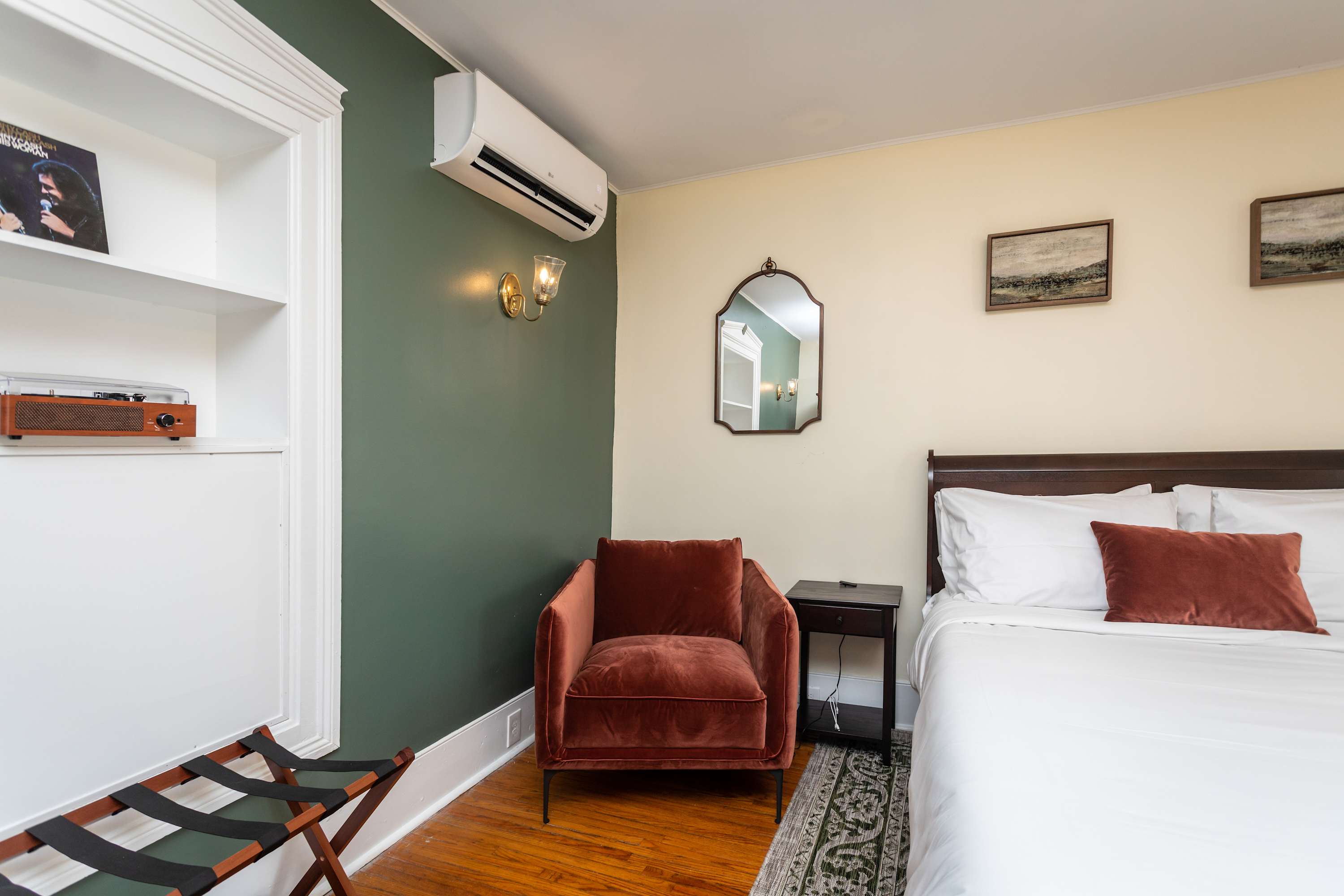 Cozy bedroom corner with a rust-colored armchair and air conditioning on a green accent wall