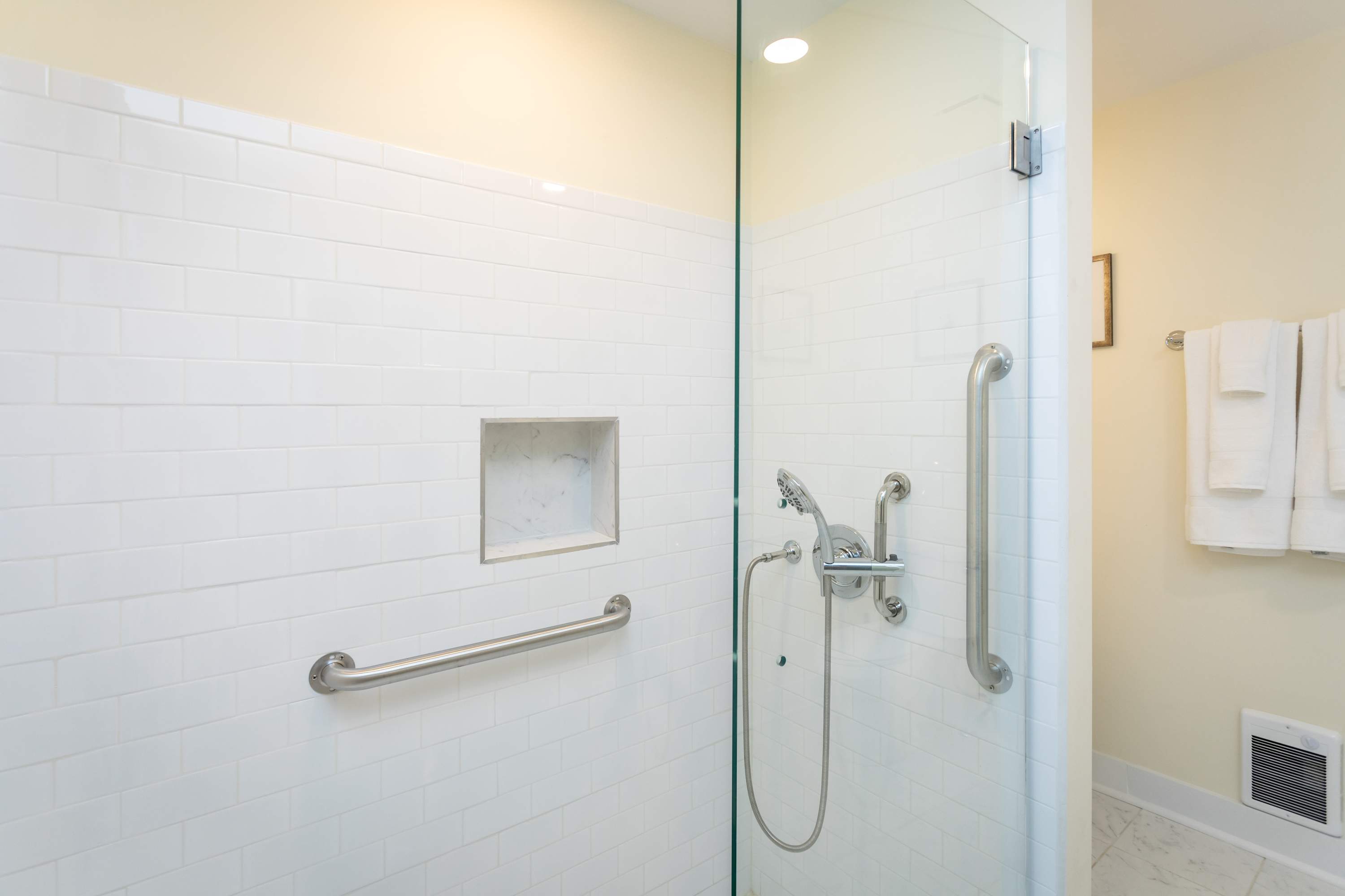Modern shower with white subway tiles and safety grab bars
