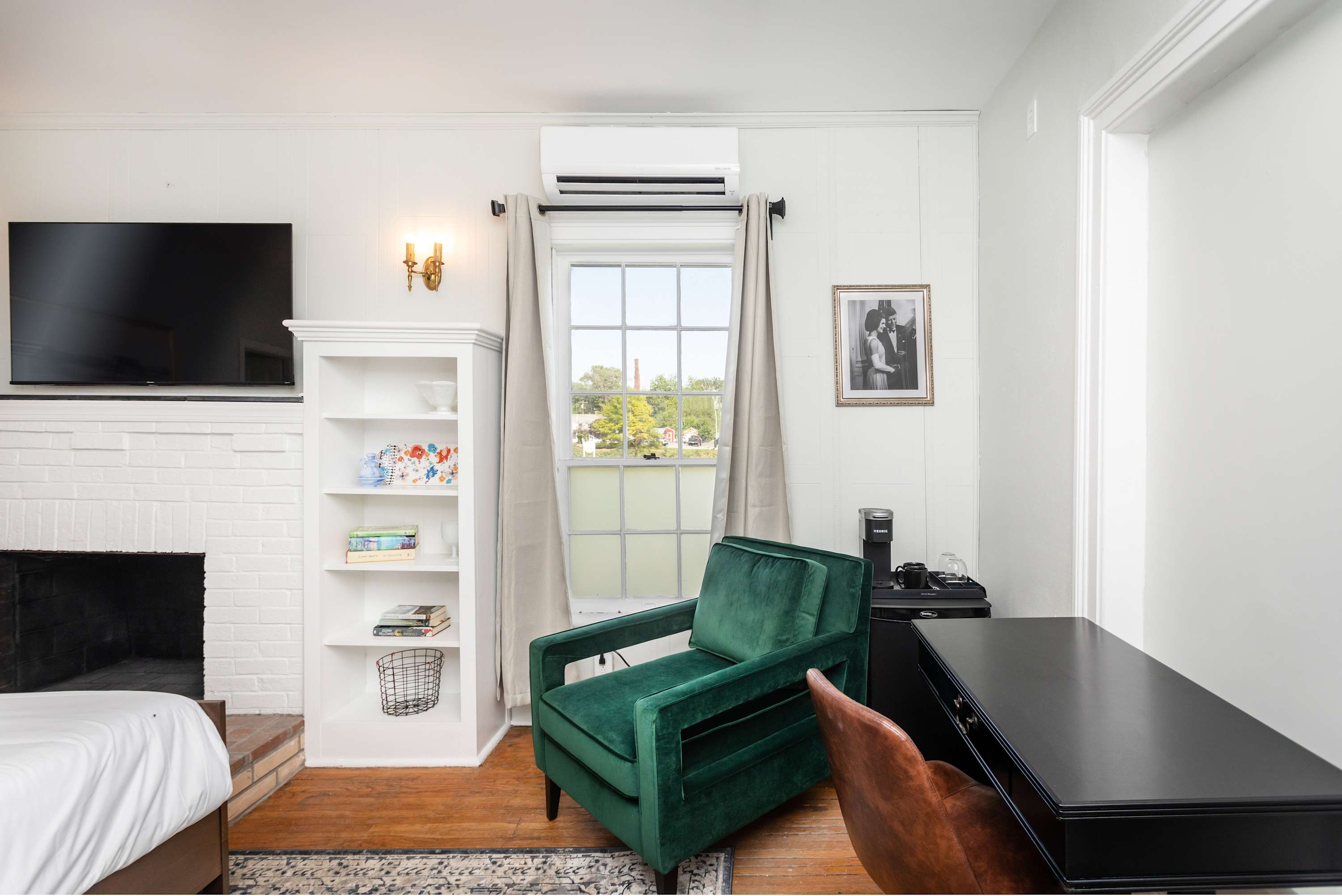 Cozy sitting area with a green velvet armchair, fireplace, and natural light from the window.