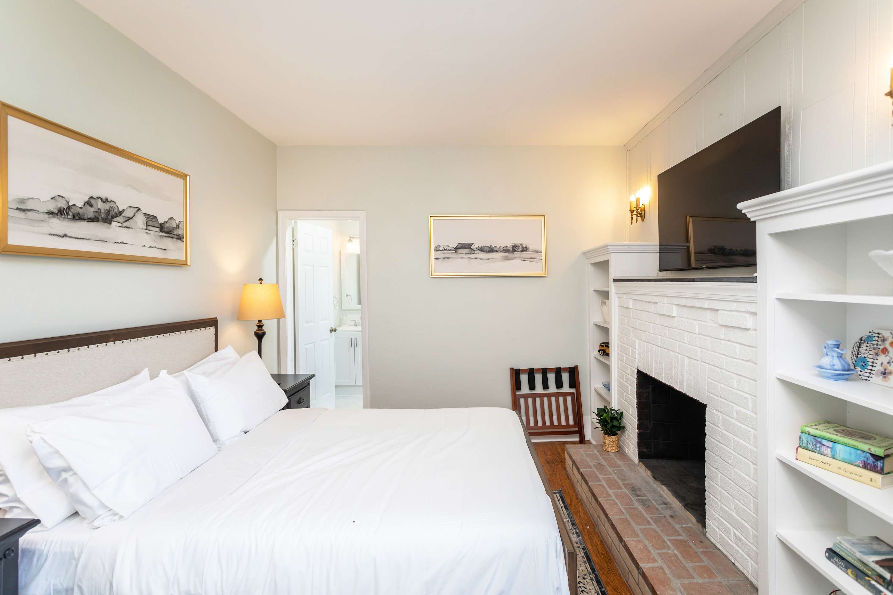 Bright bedroom with a white brick fireplace and mounted television