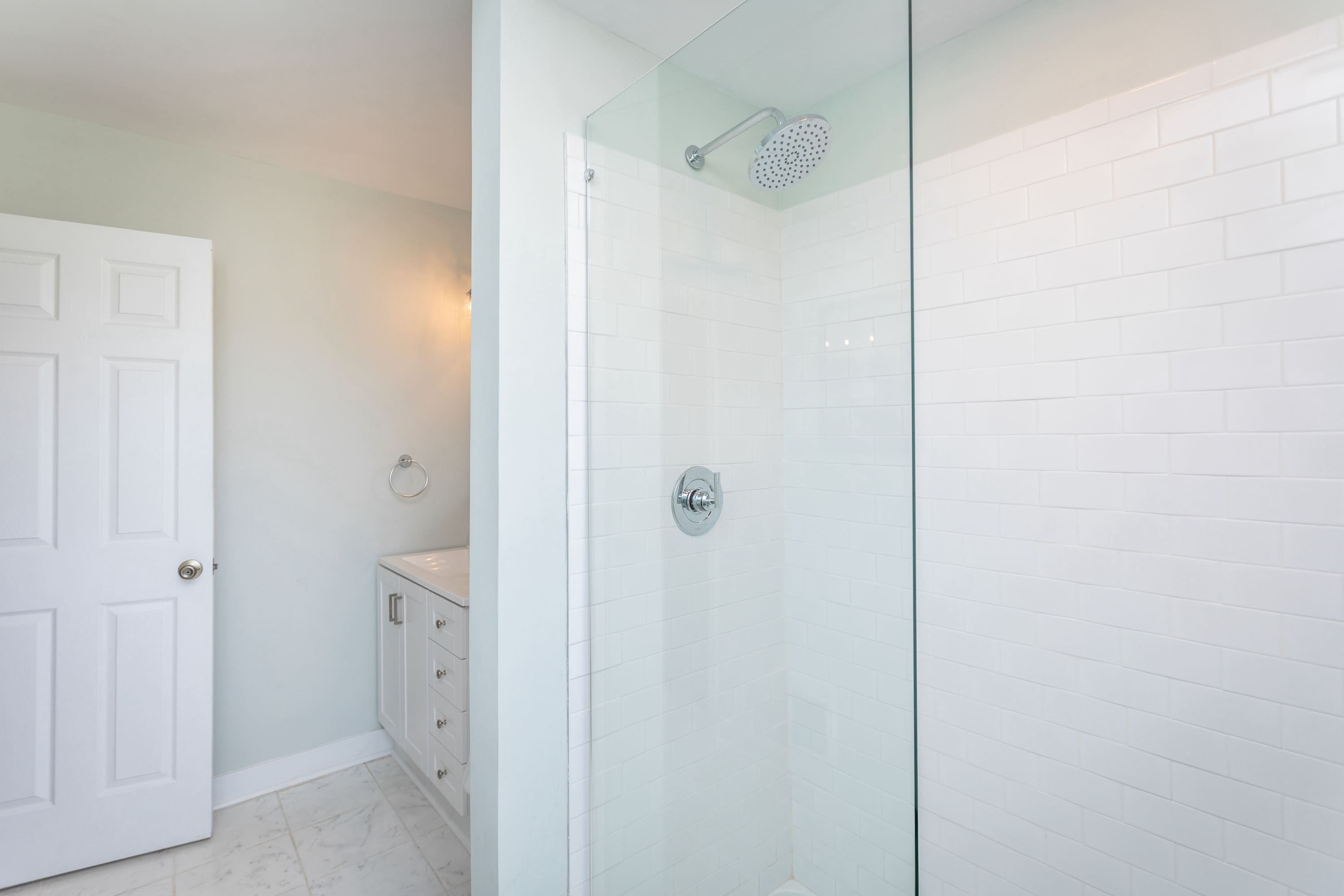 Modern bathroom featuring a walk-in shower with white subway tile and a glass partition.