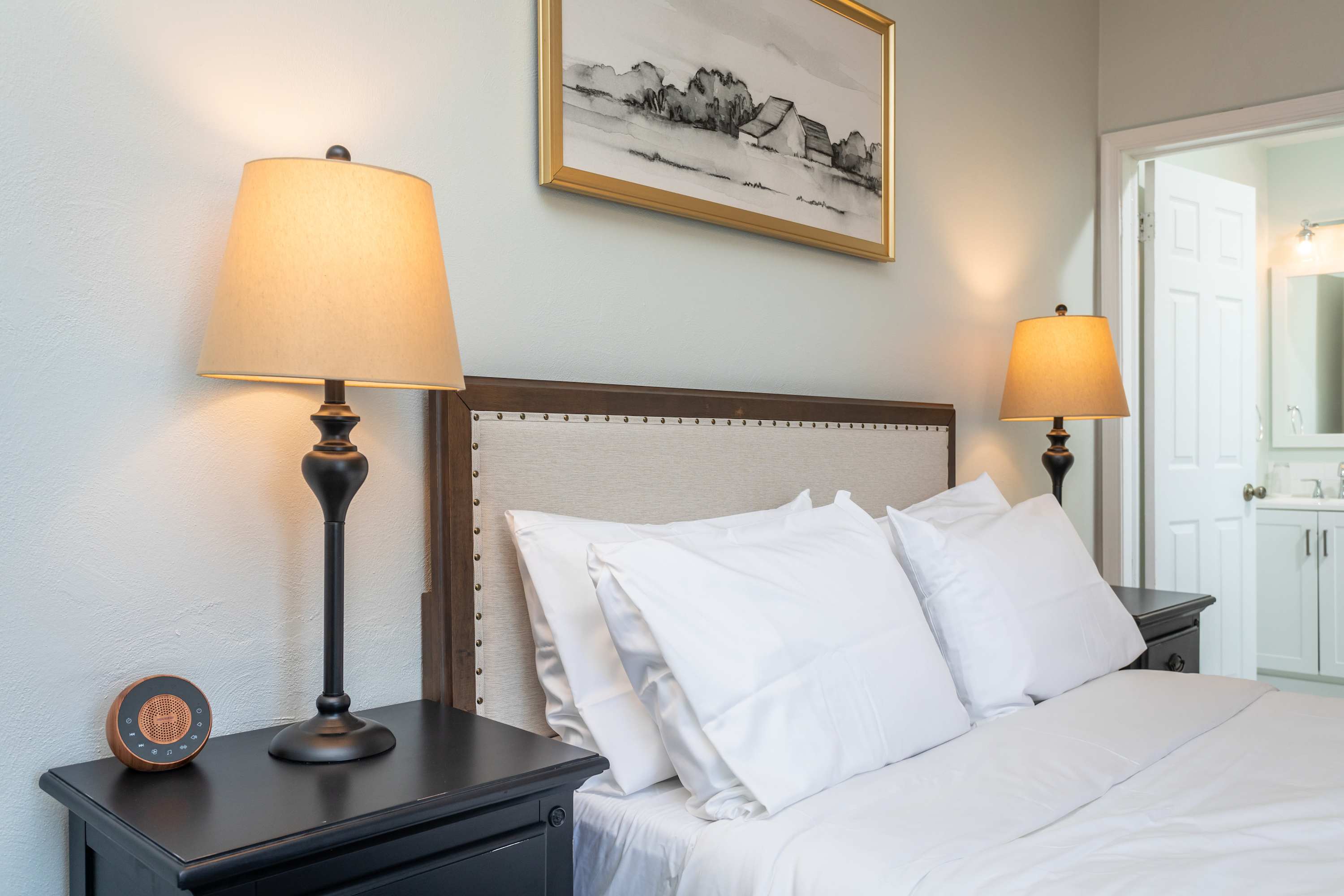 Cozy bedroom with a cushioned headboard and warm bedside lamps.
