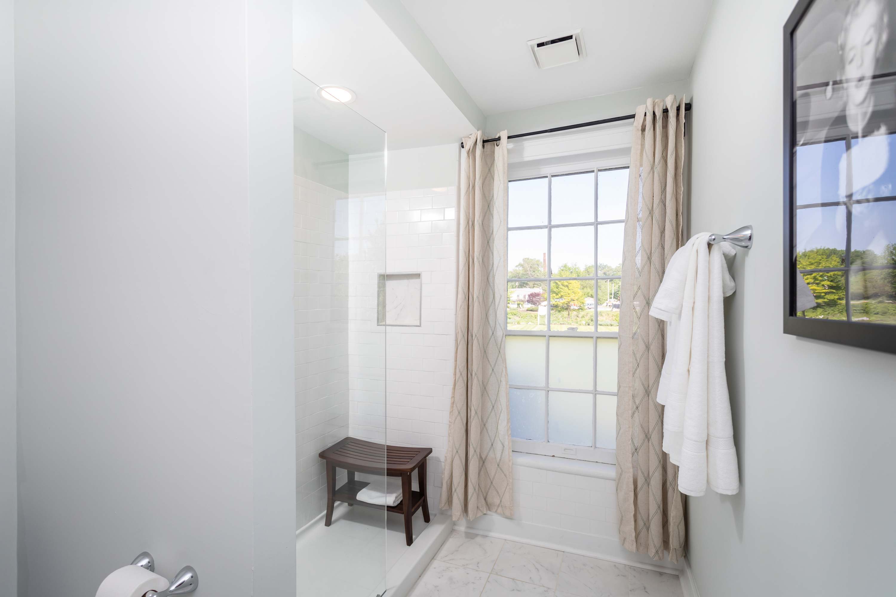 Bright bathroom with a walk-in shower and natural light from a large window